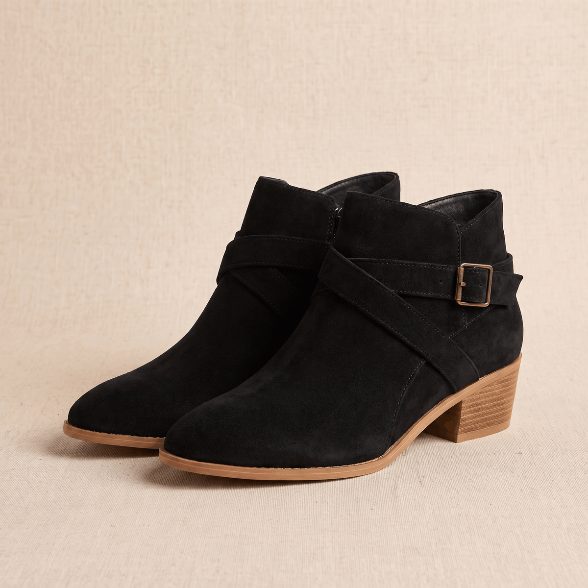 Pair of black suede ankle boots with side buckle on a neutral background.