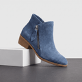 Blue suede ankle boots with side zippers and block heels displayed on a white pedestal.