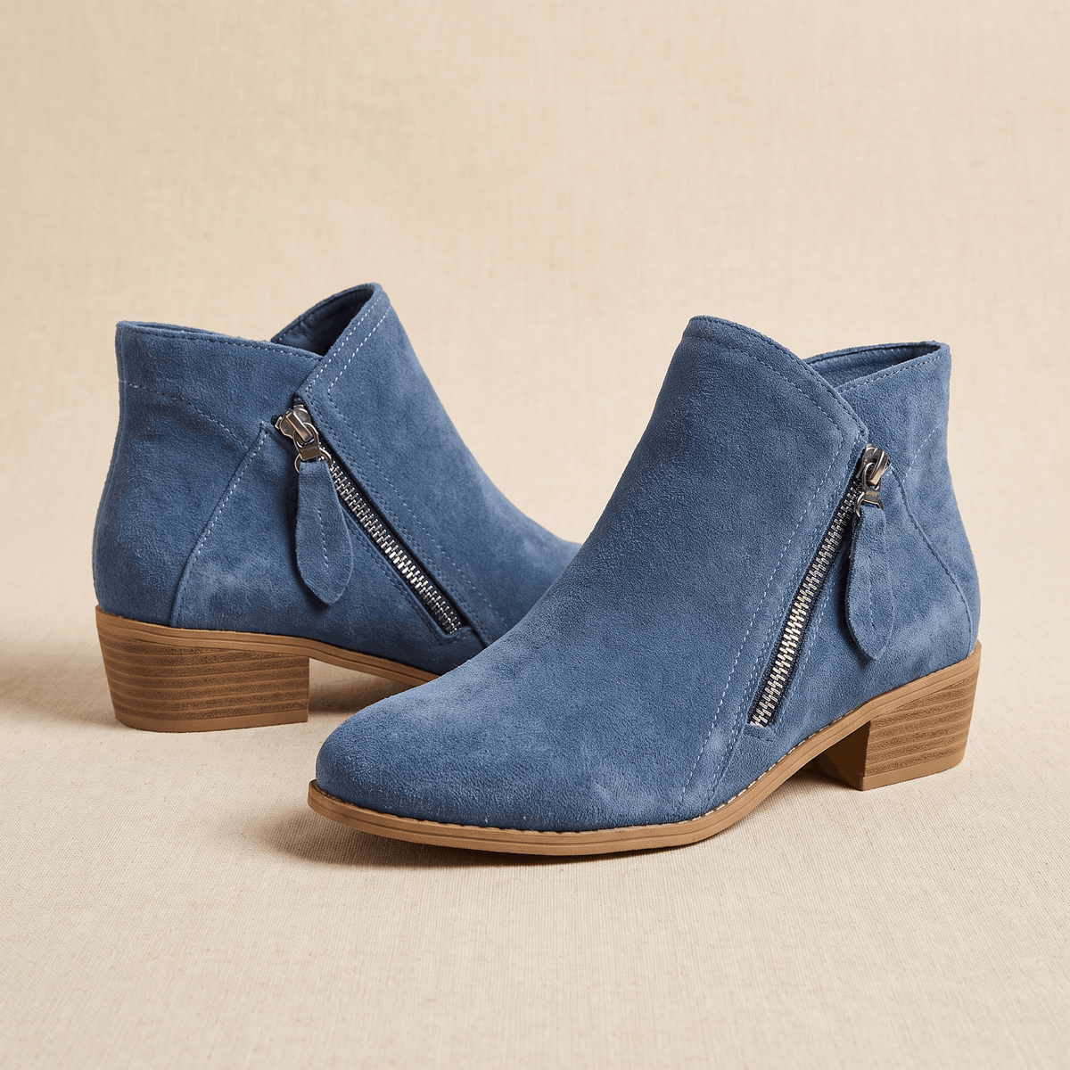 Pair of blue suede ankle boots with side zippers on a neutral background.