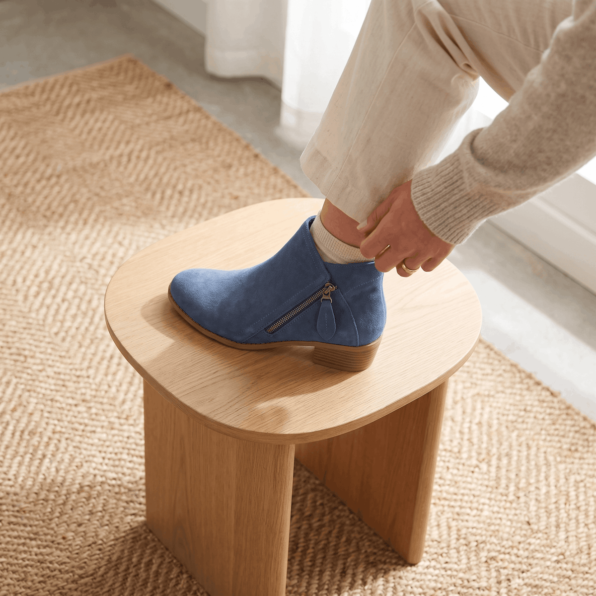 Close-up of blue suede ankle boots being worn indoors.