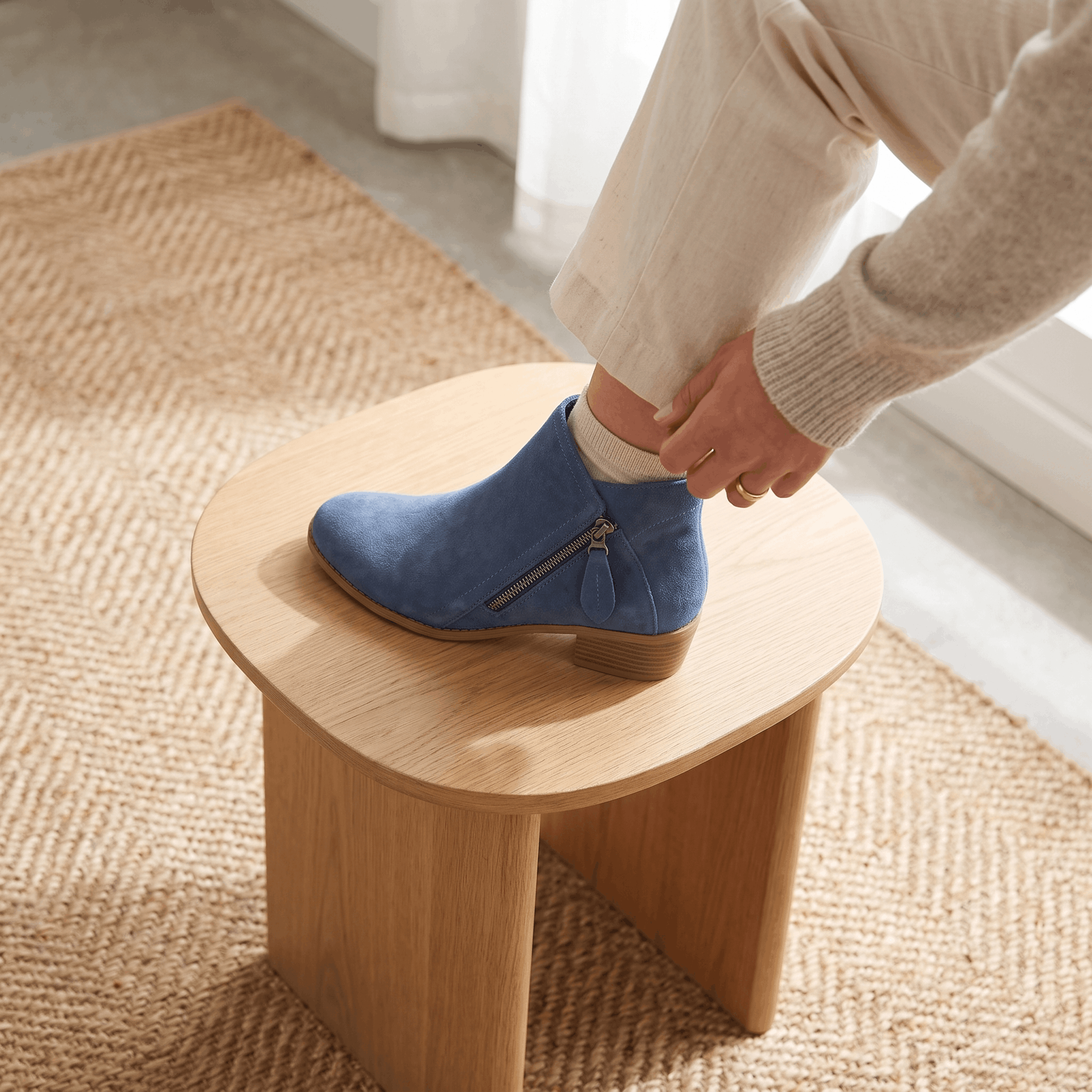 Close-up of blue suede ankle boots being worn indoors.