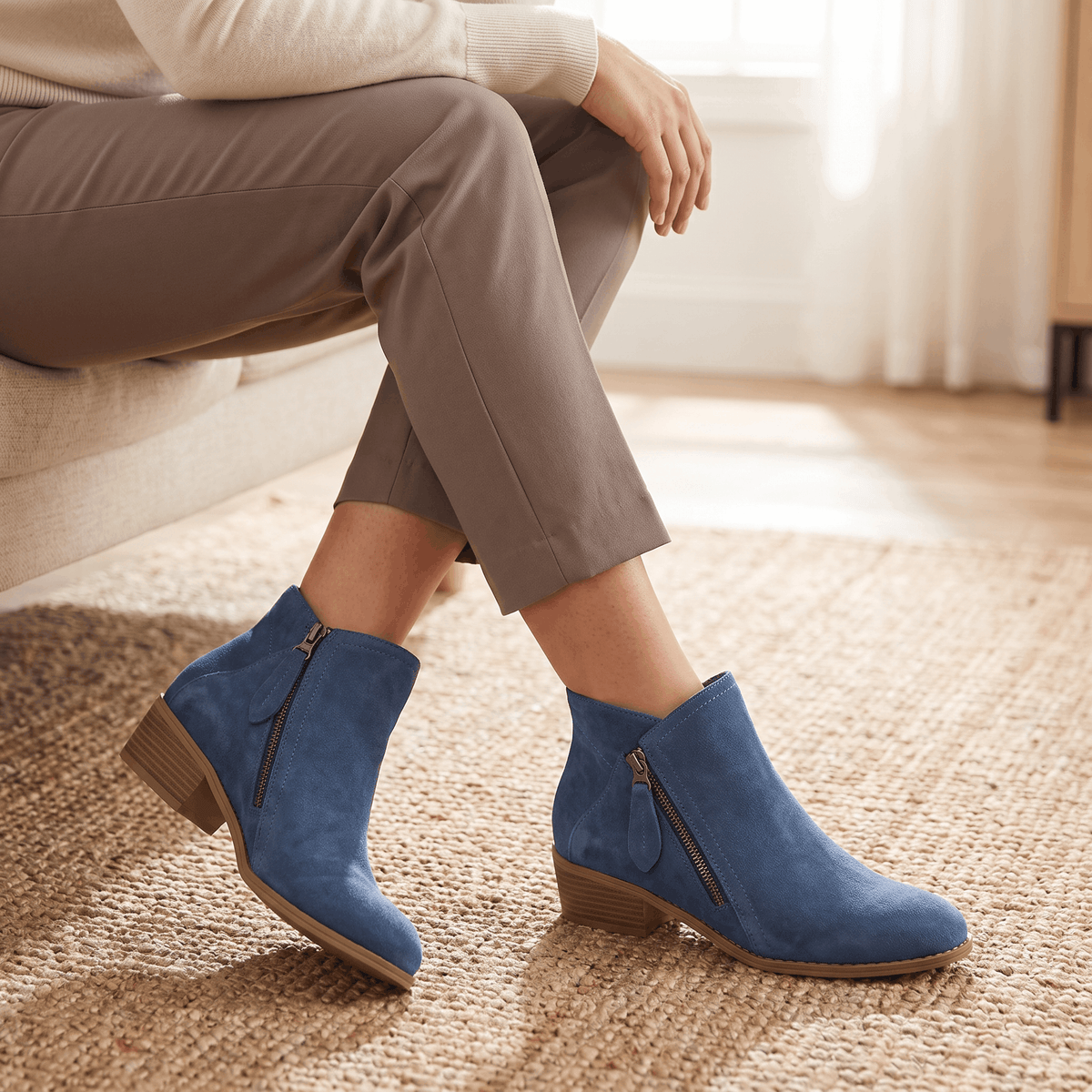 Woman wearing blue suede ankle boots with beige trousers.