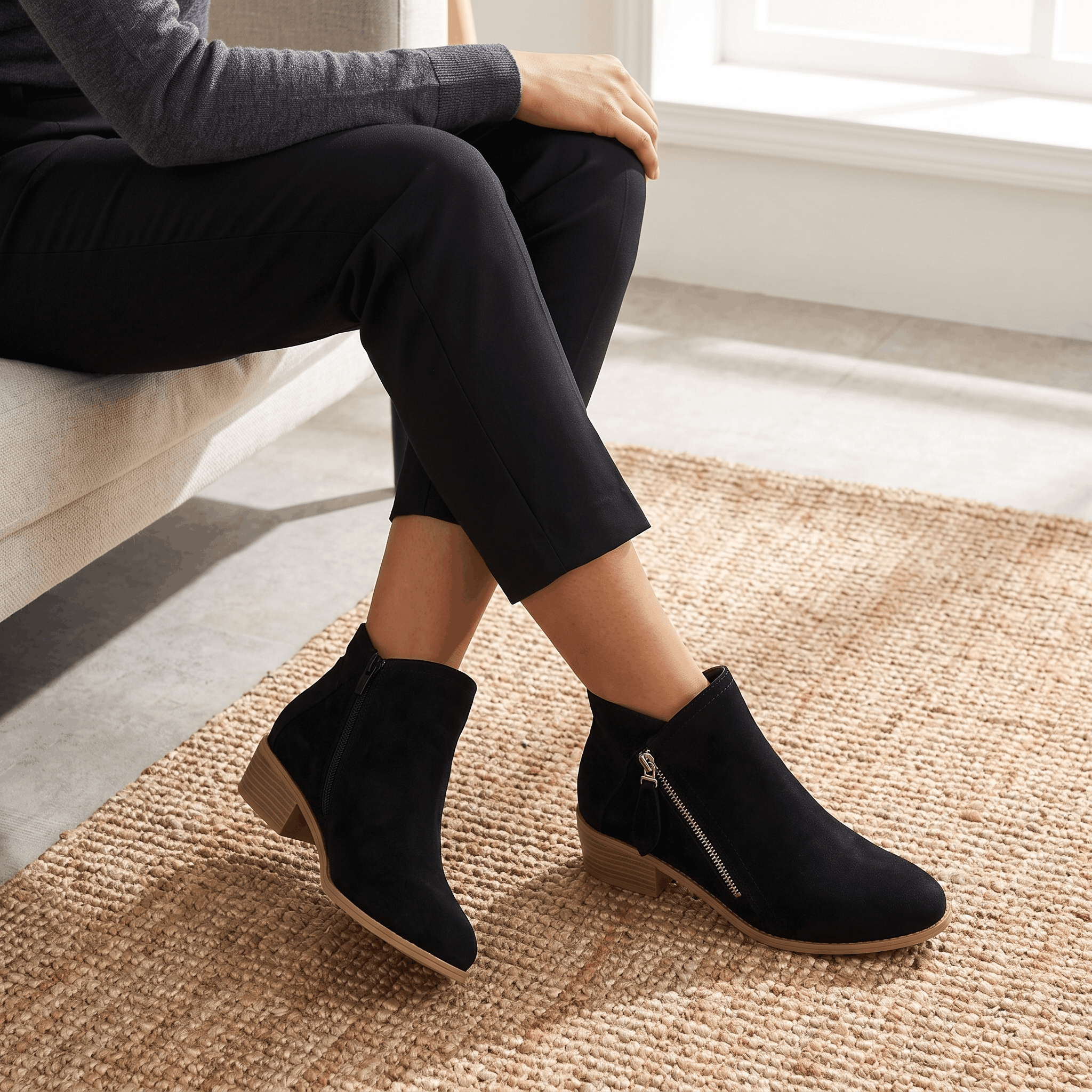 Woman wearing black suede ankle boots with dark trousers.