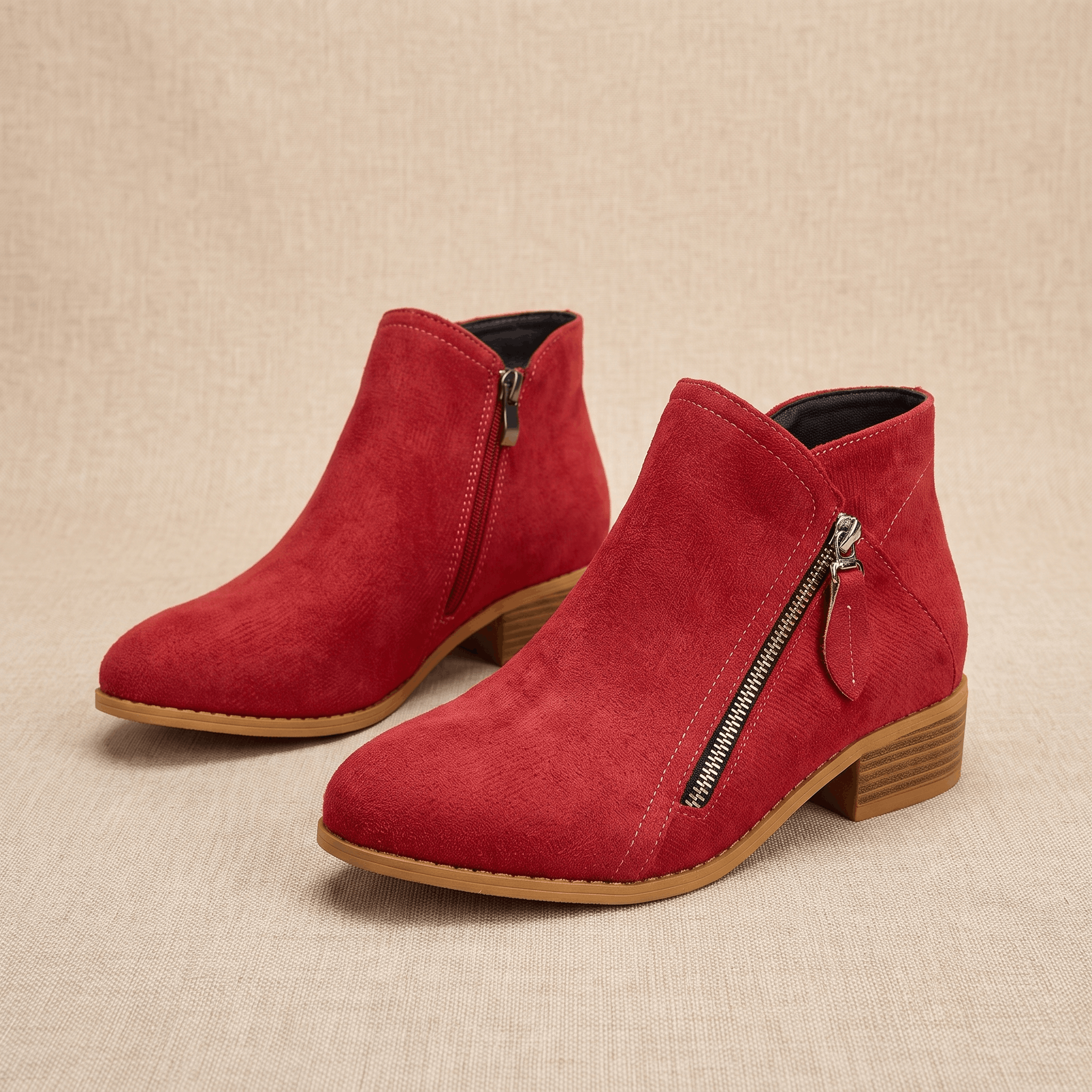 Pair of red suede ankle boots with side zippers on a neutral background.