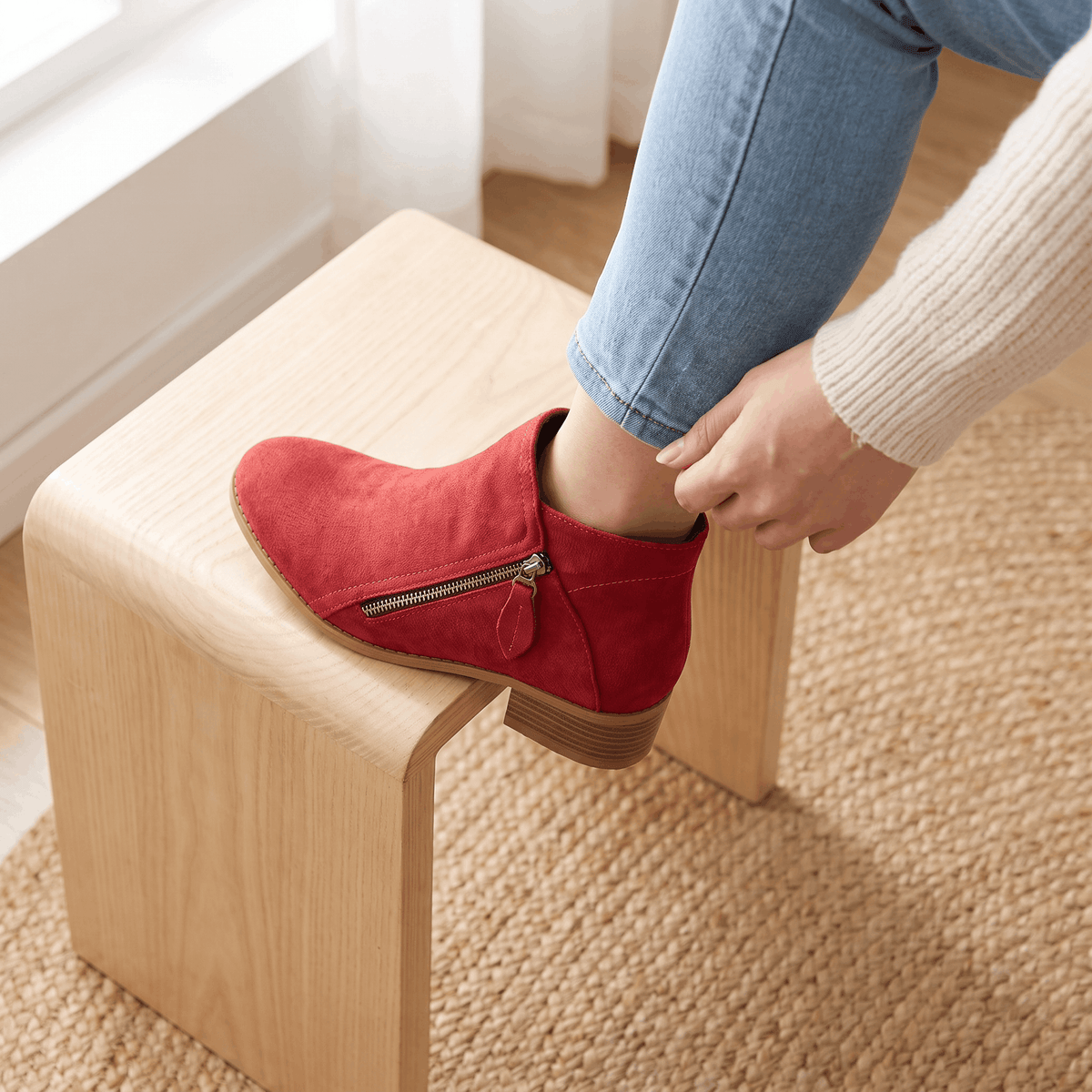 Red suede ankle boots with side zippers worn with blue jeans.