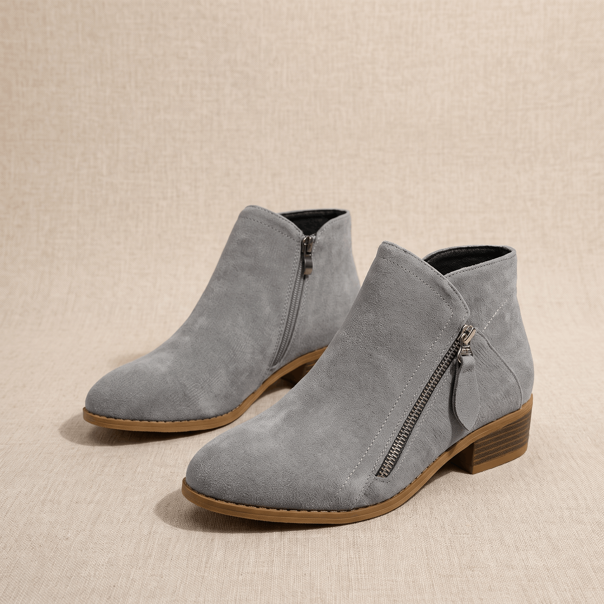 Pair of gray suede ankle boots with side zippers on a neutral background.
