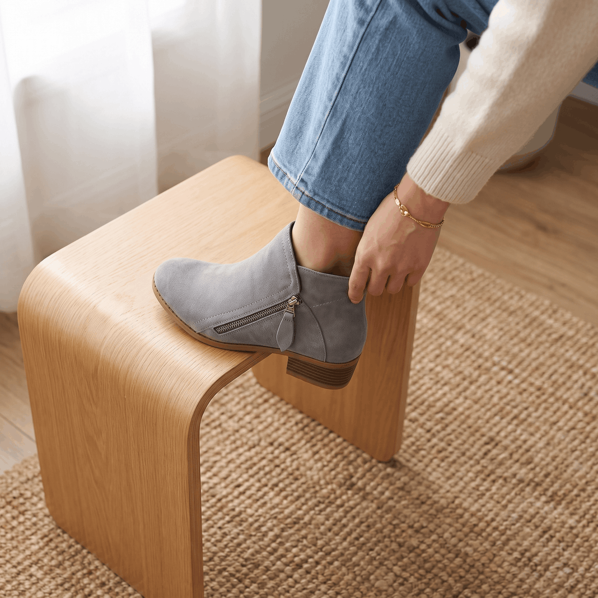 Close-up of gray suede ankle boots being worn indoors.