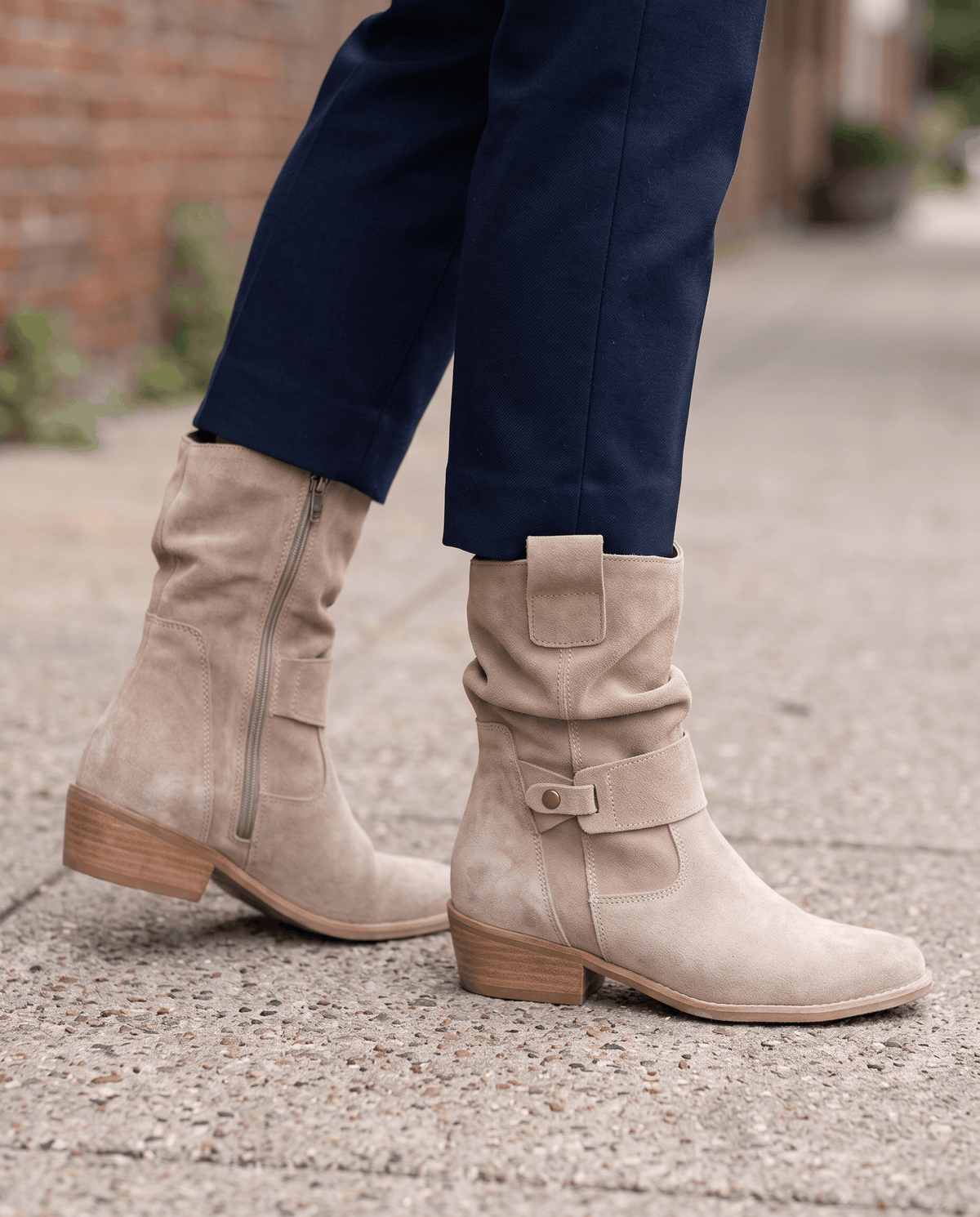 Beige suede slouch boots worn with navy trousers outdoors