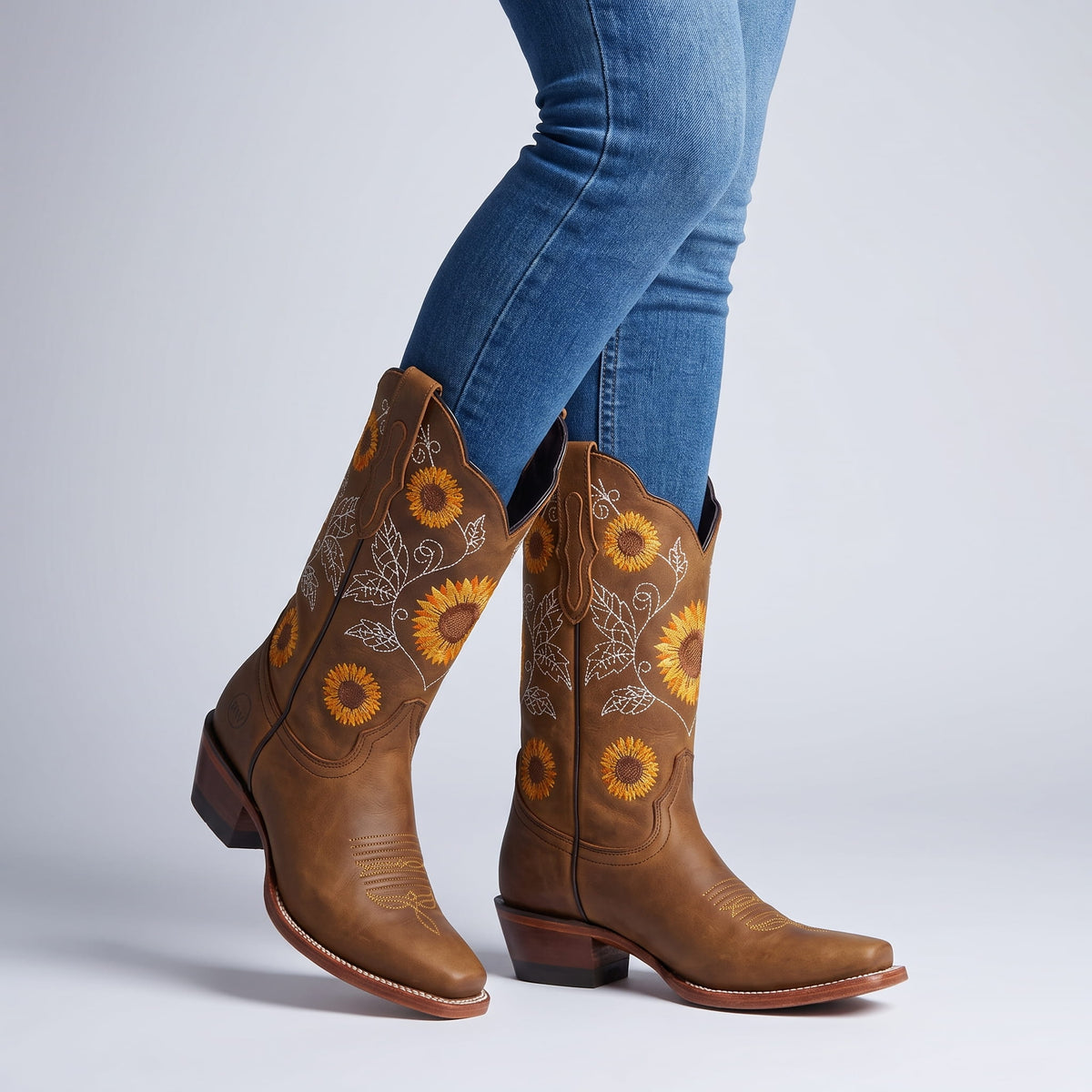 Woman in blue jeans walking in brown boots with sunflower embroidery