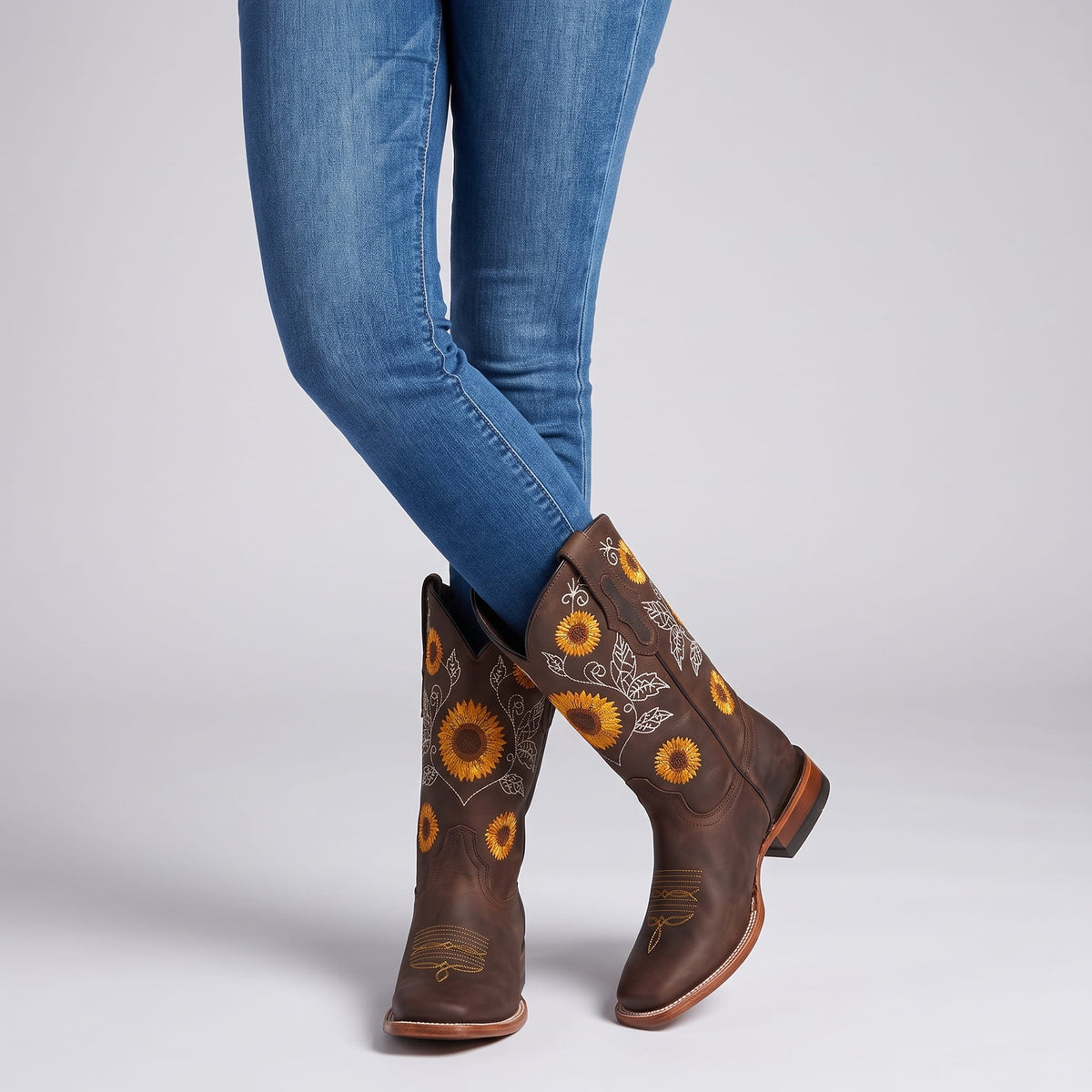 Woman in blue jeans standing in dark brown sunflower cowboy boots