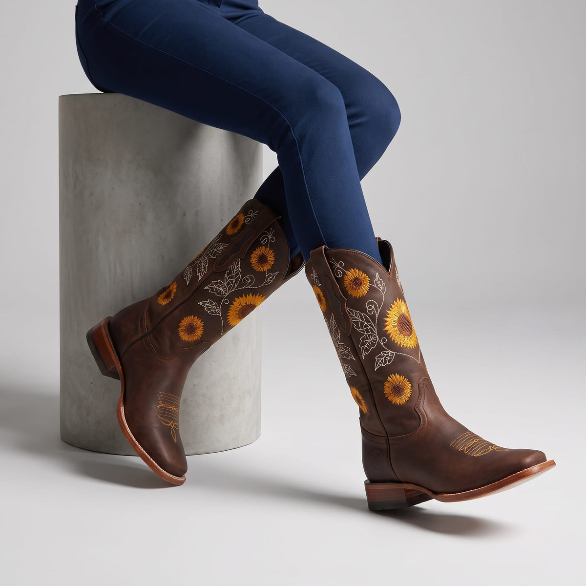 Seated woman in navy leggings wearing dark brown embroidered boots