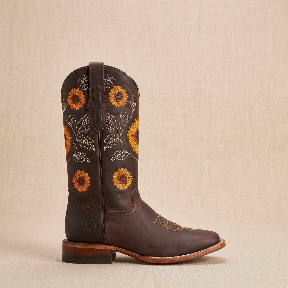 Single dark brown boot in side profile on a beige backdrop