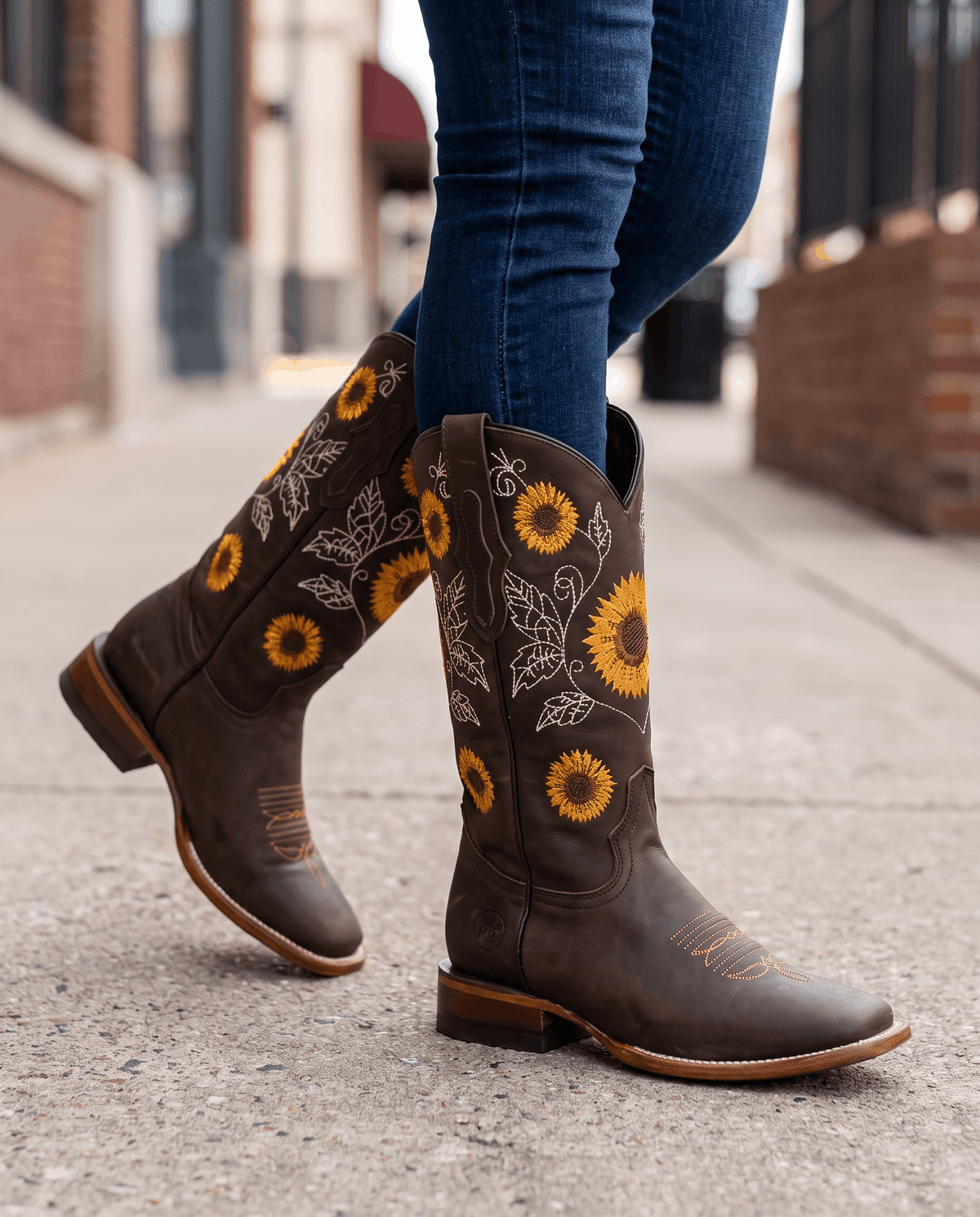 Close view of dark brown boots on a sidewalk showing the sunflower shaft