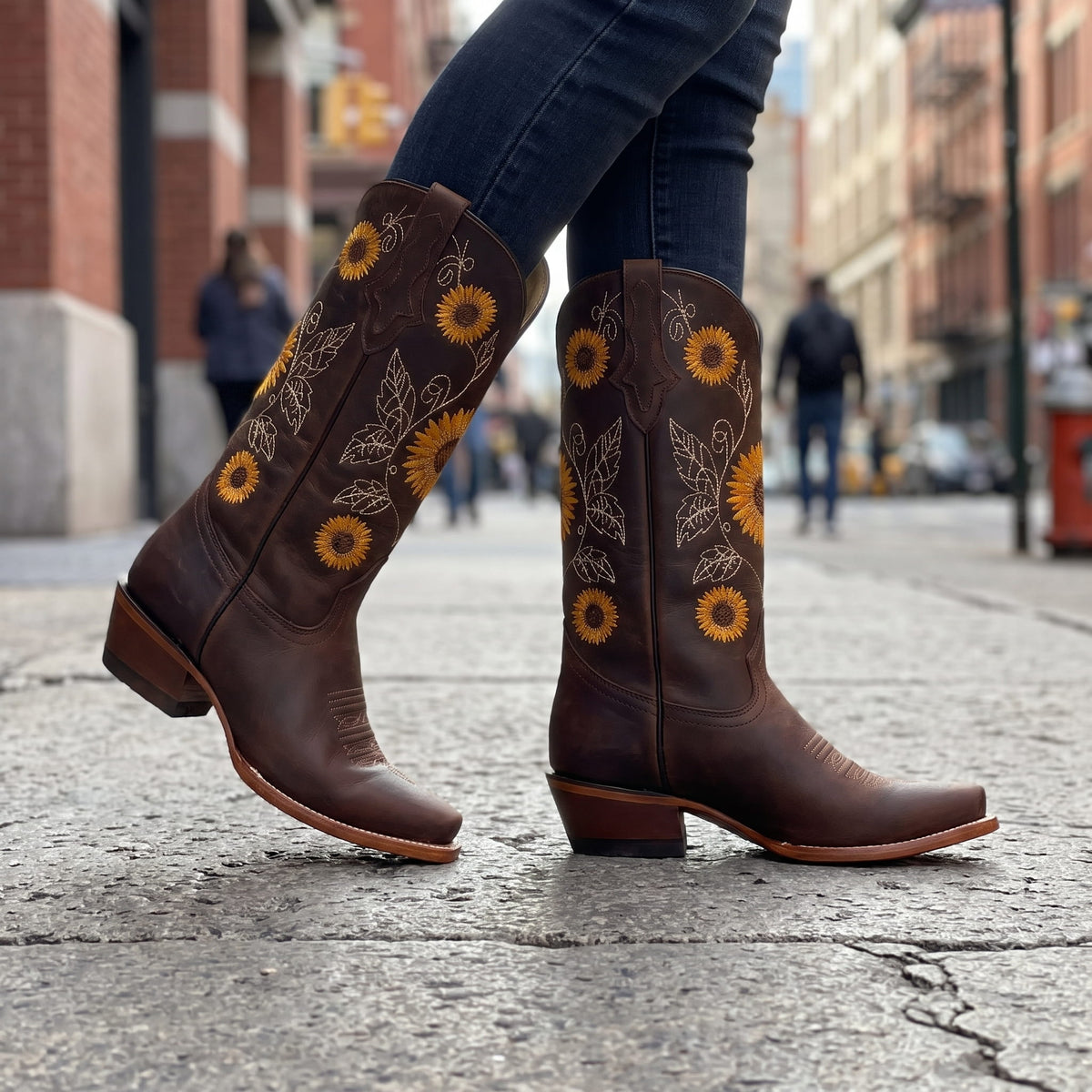 Woman in dark jeans walking on a city street in dark brown western boots