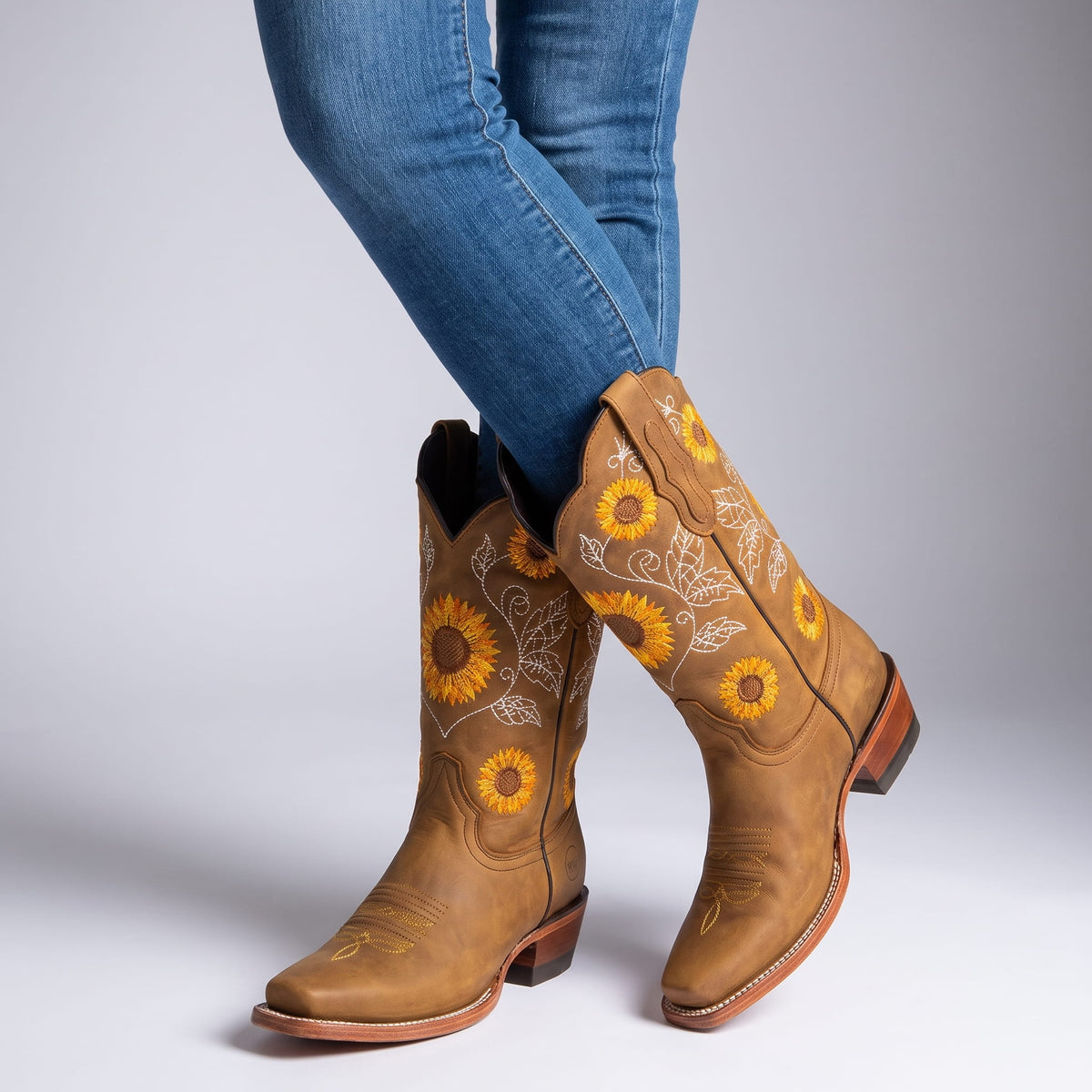 Woman in blue jeans with crossed legs wearing khaki sunflower boots