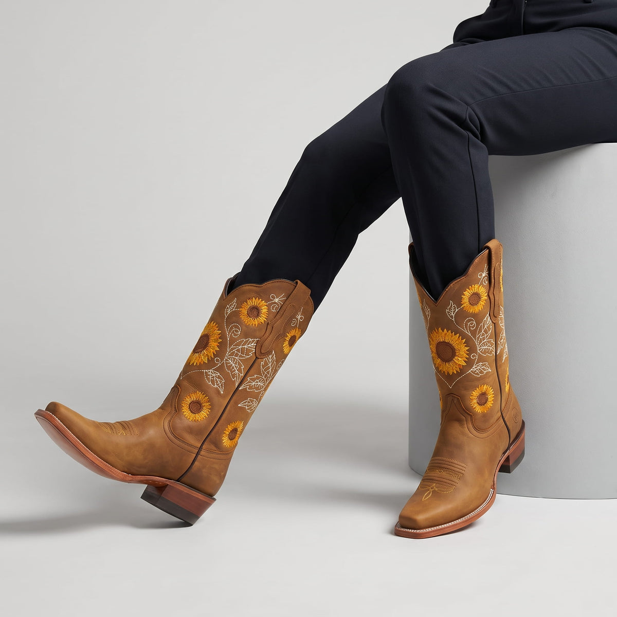 Seated woman in black trousers wearing khaki western boots