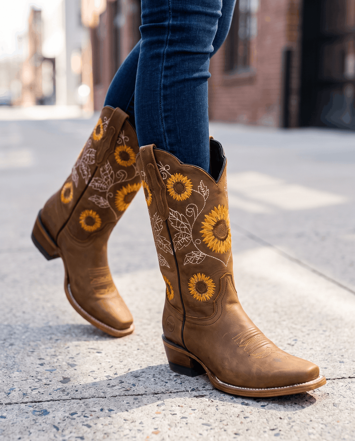 Woman in jeans walking on a city sidewalk in khaki cowboy boots