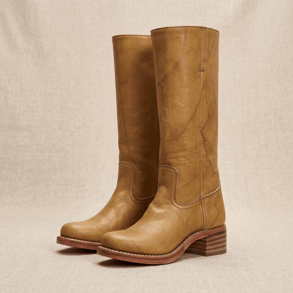 Pair of tan vegan leather knee-high riding boots on a neutral background.