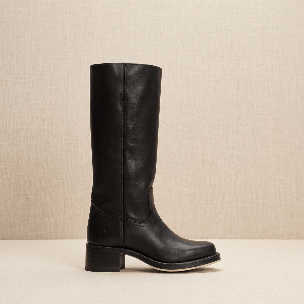 Woman wearing black vegan leather knee-high riding boots with blue jeans.