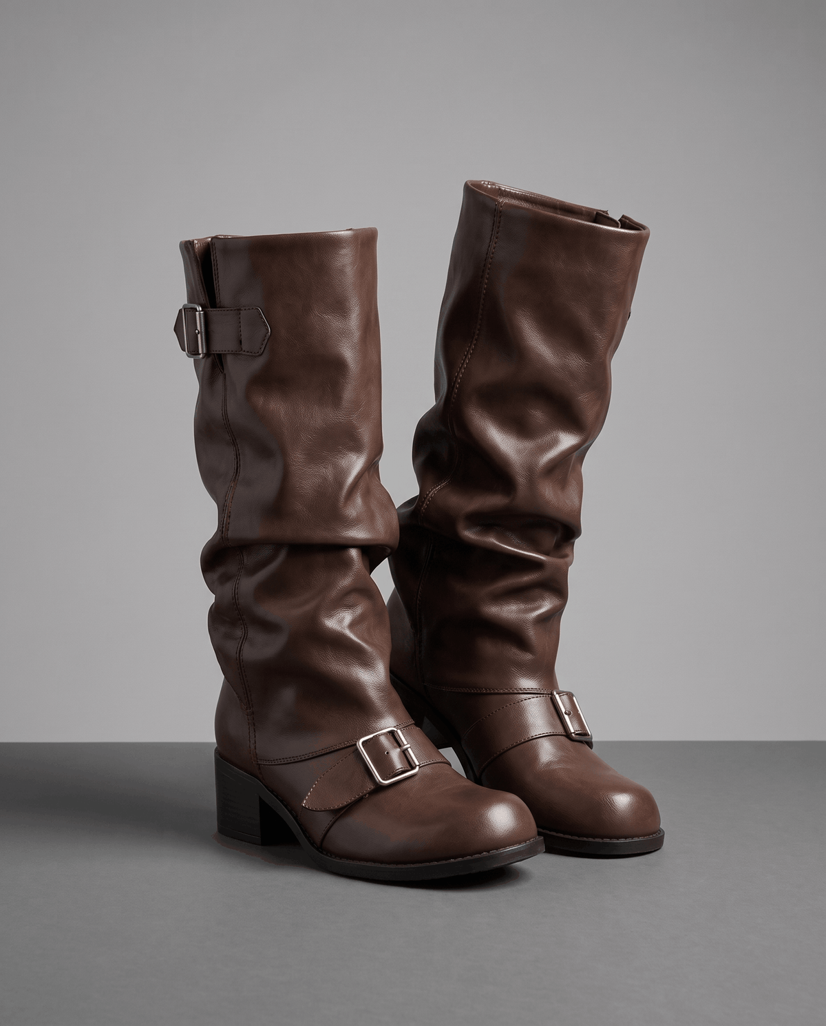 Brown vegan leather mid-calf boots with a ruched slouch shaft, stacked block heels, and double buckle strap detailing.