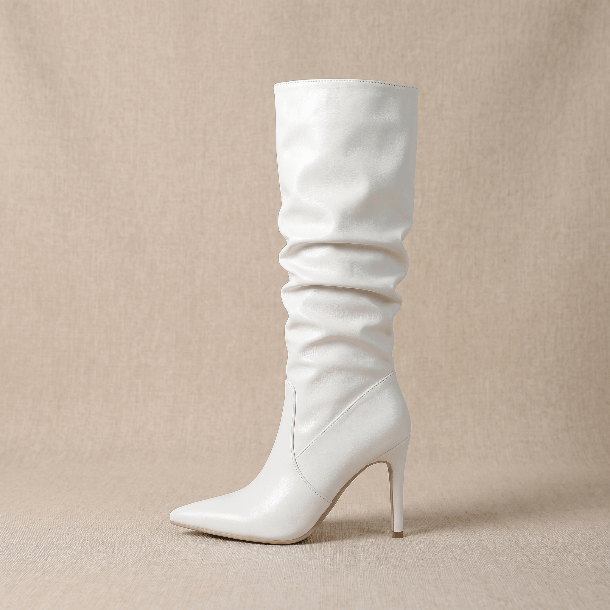White vegan leather knee-high stiletto boots with a ruched slouch shaft and a sharp pointed toe.