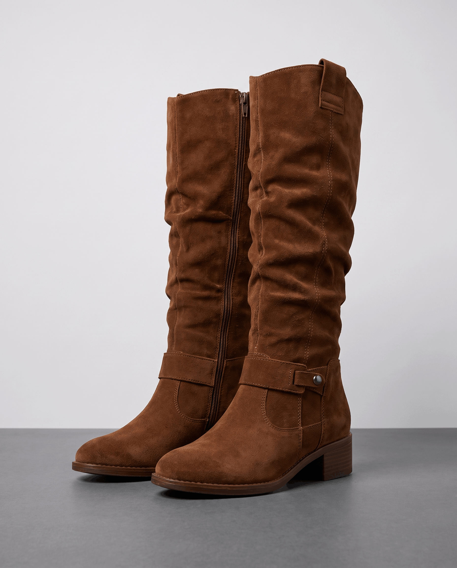 Dark brown vegan suede knee-high slouch boots with a side zip and ankle strap, displayed against a white studio background.