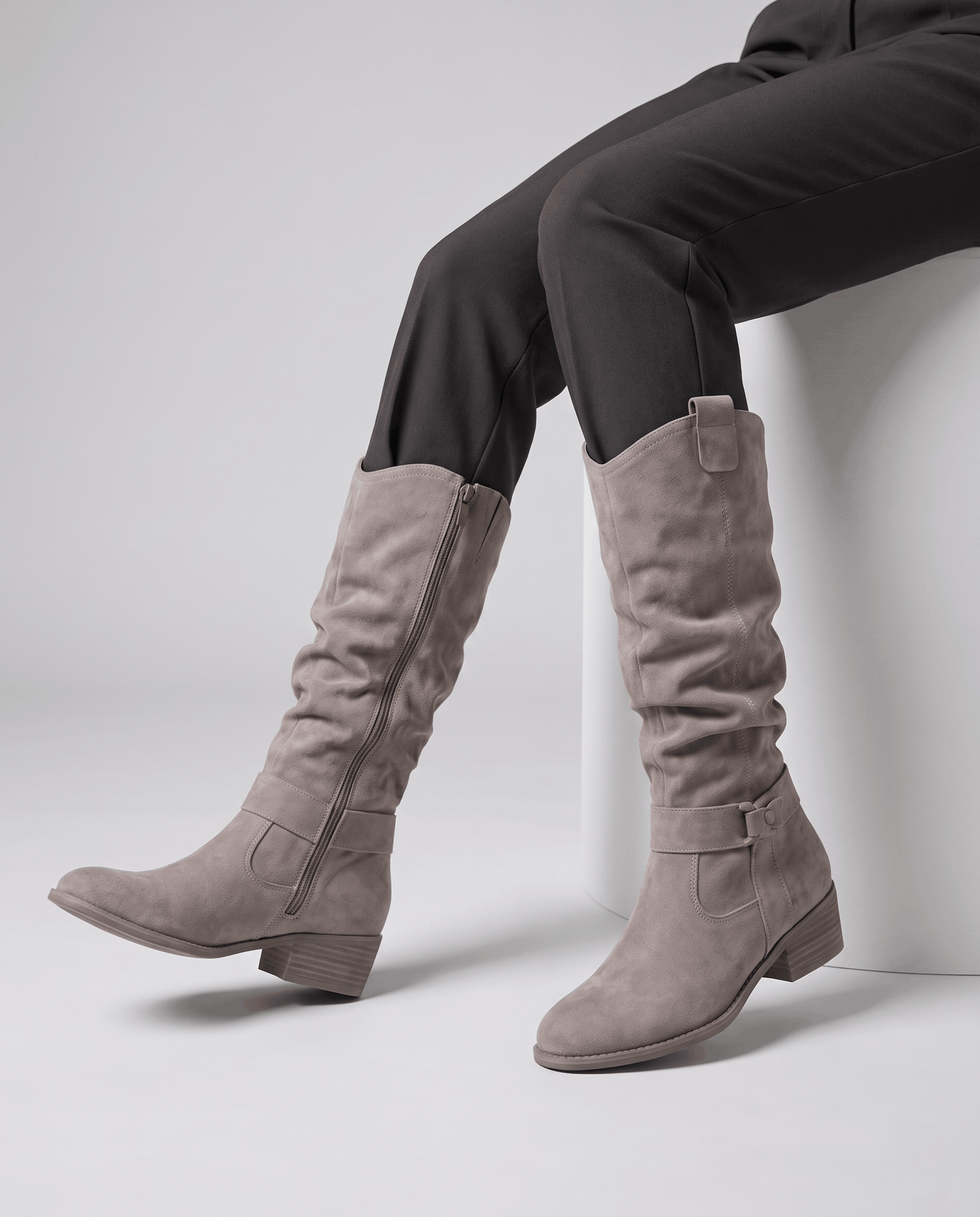 Woman wearing gray vegan suede knee-high slouch boots with dark pants.