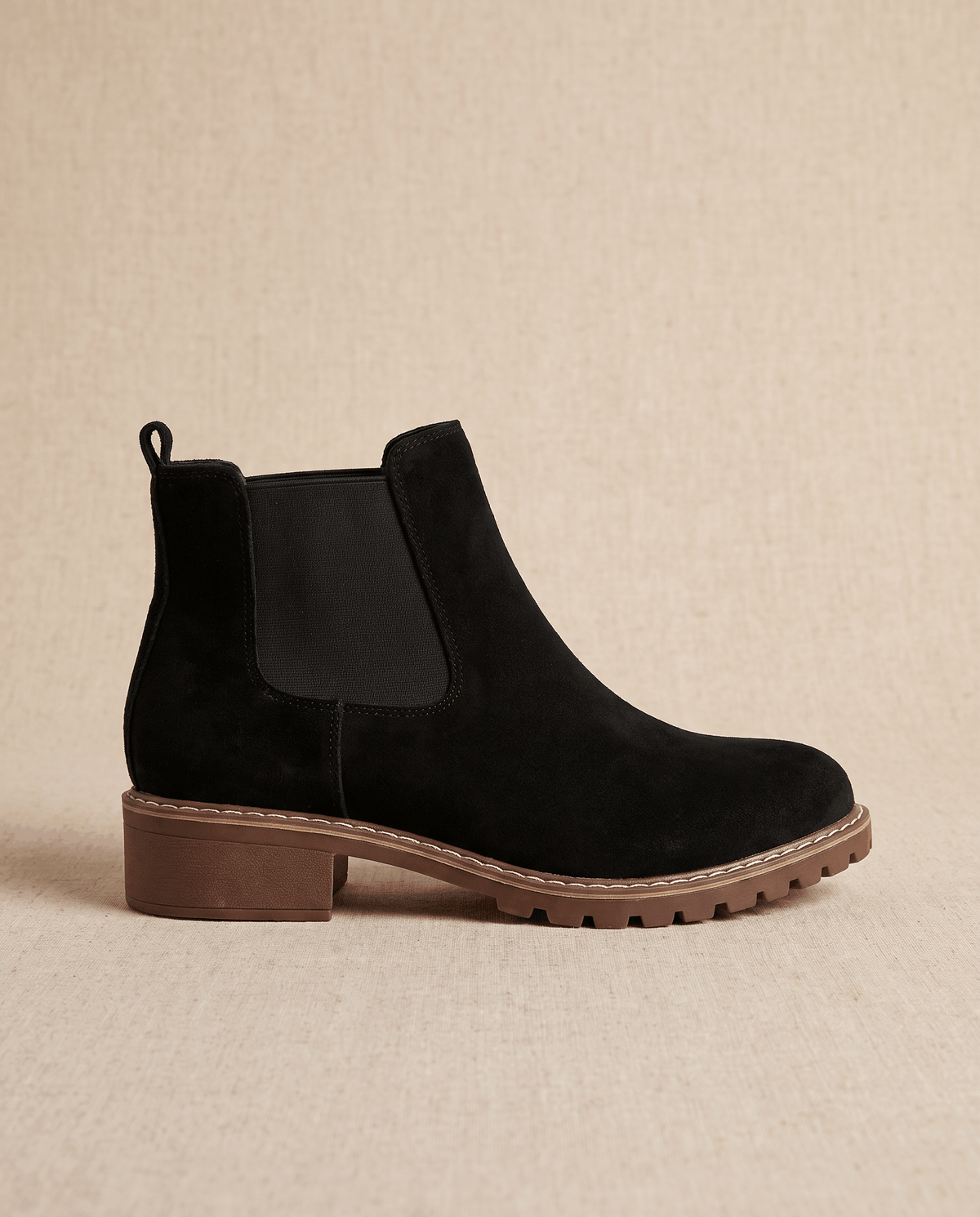 Black vegan suede Chelsea boot with elastic side panels, a stitched welt, and a chunky brown lug outsole.