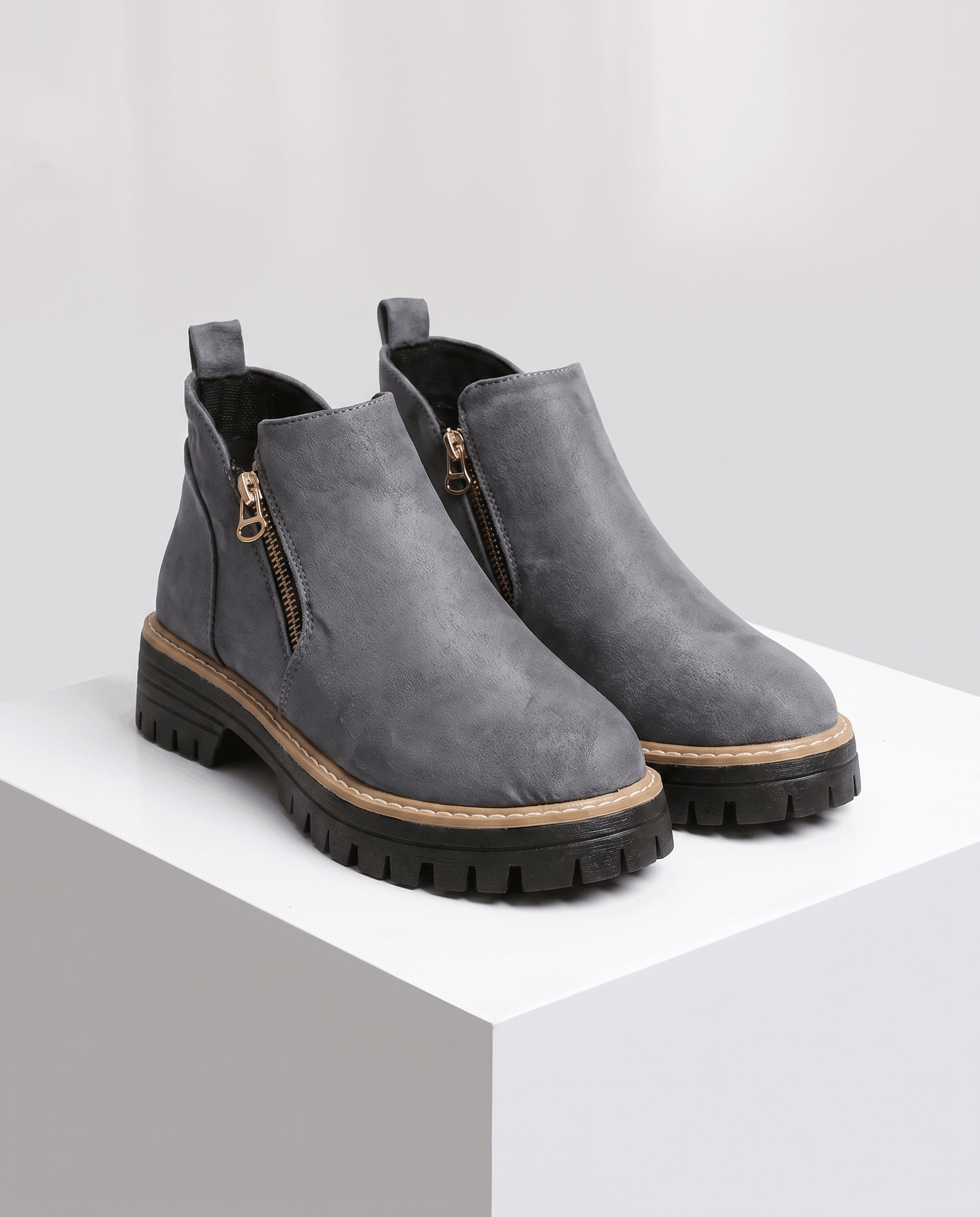 Gray vegan suede ankle boots with side zips, chunky lug platforms, and cushioned wedge soles on a white pedestal.