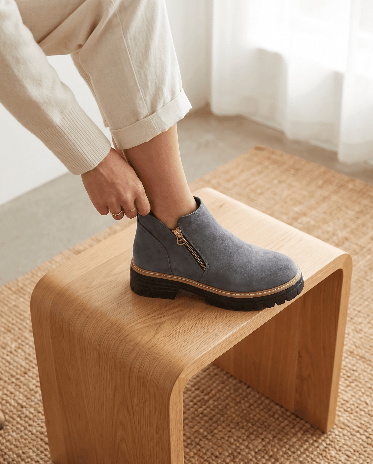 Gray vegan suede ankle boots with a side zip, chunky lug platform, and cushioned wedge sole worn with cream trousers.