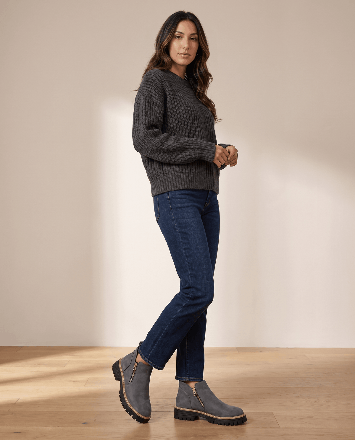 Gray vegan suede ankle boots with side zips and chunky lug platform soles worn with dark blue jeans and a grey sweater.