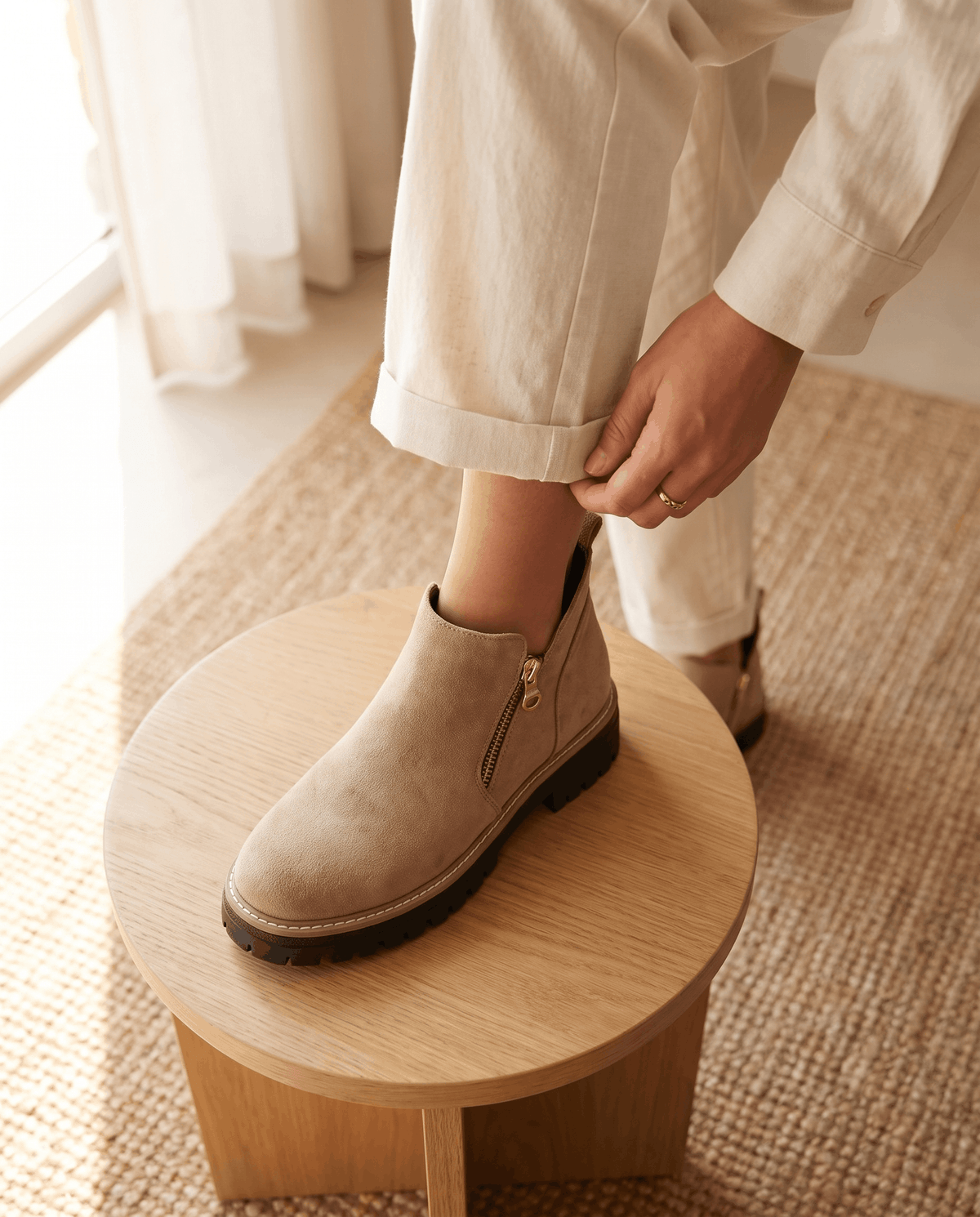 Taupe vegan suede ankle boots with a side zip, chunky lug platform, and cushioned wedge sole worn with cream trousers.