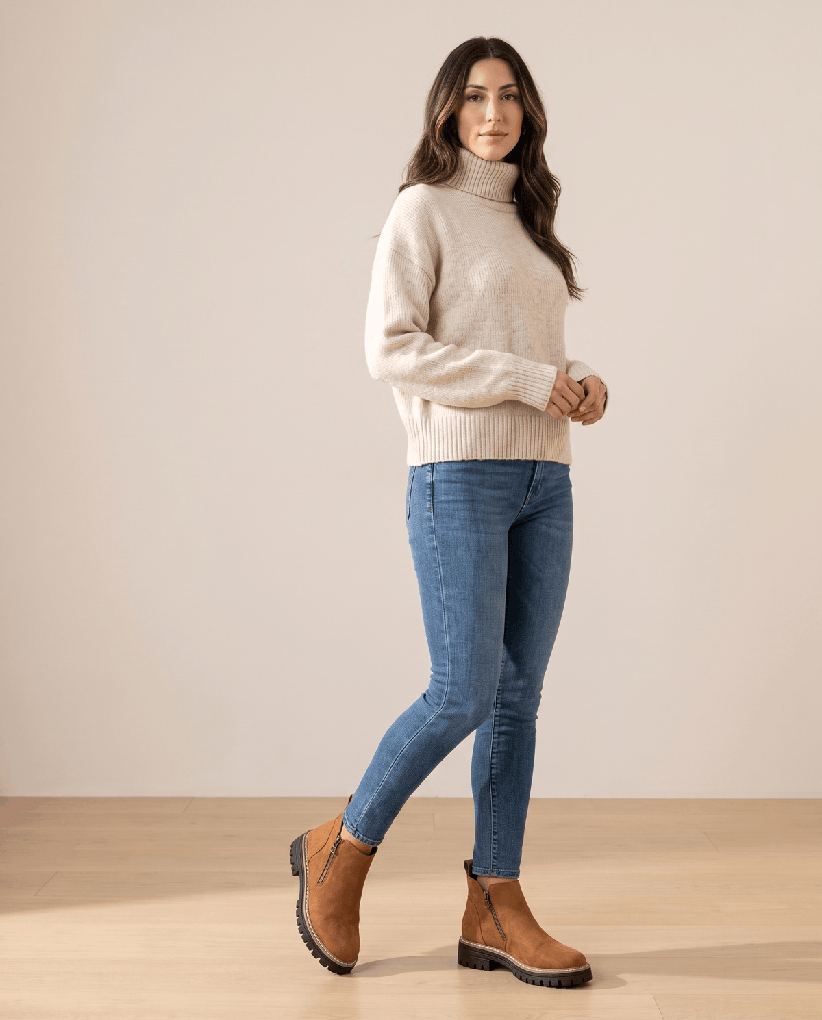 Tan vegan suede ankle boots with side zips and chunky lug platform soles worn with blue jeans and a cream turtleneck.