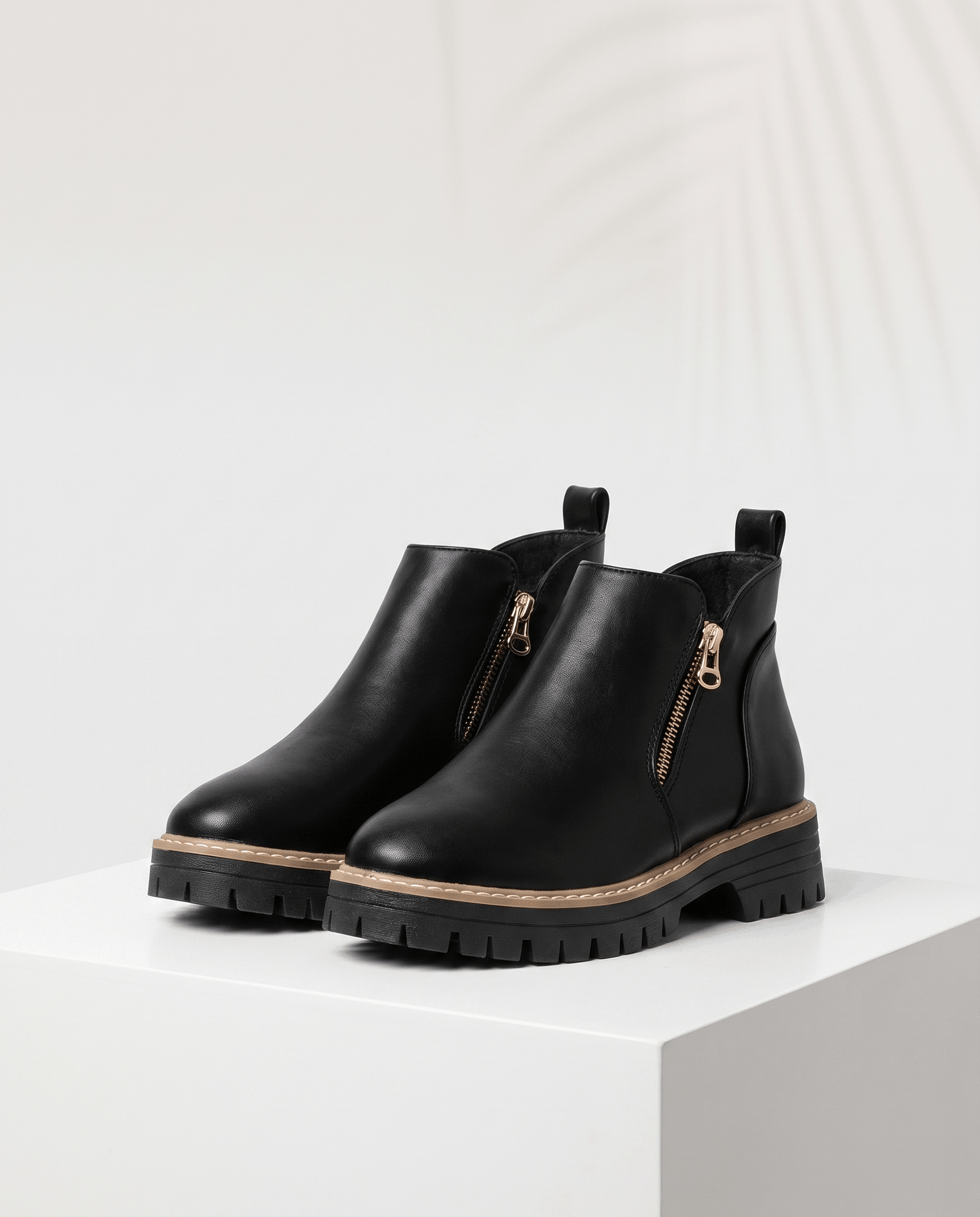 Black vegan suede ankle boots with side zips, a matte finish, and a chunky lug platform wedge sole on a white pedestal.
