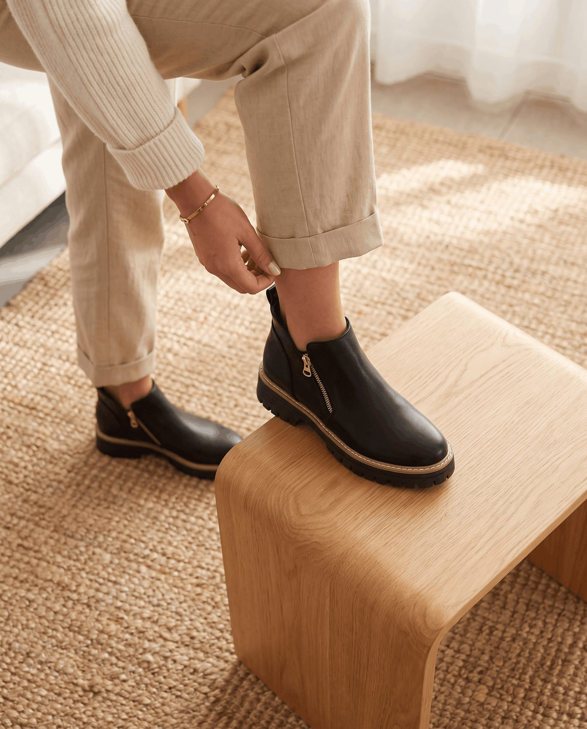 Black vegan suede ankle boots with side zips, chunky lug platforms, and cushioned wedge soles worn with beige trousers.