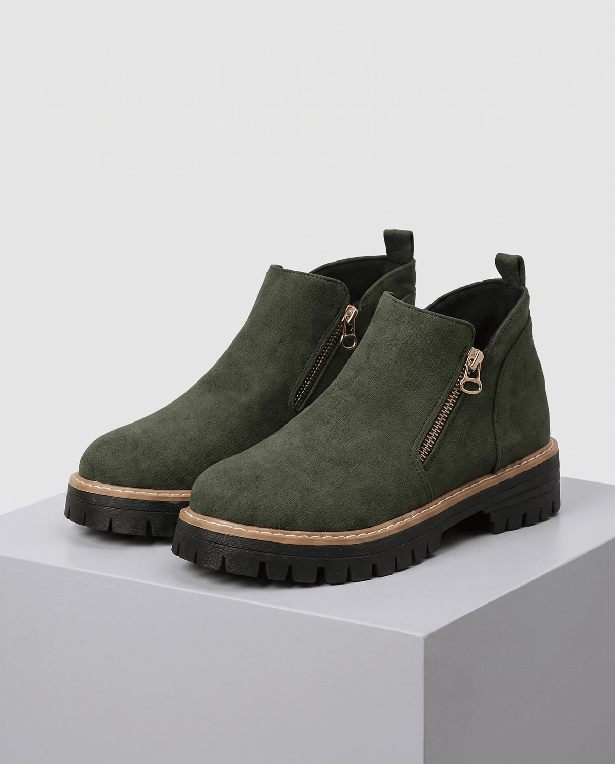 Green vegan suede ankle boots with a side zip, chunky lug platform, and cushioned wedge sole on a grey pedestal.