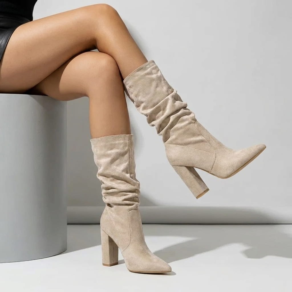 Woman seated wearing beige vegan suede mid-calf boots with a short outfit.