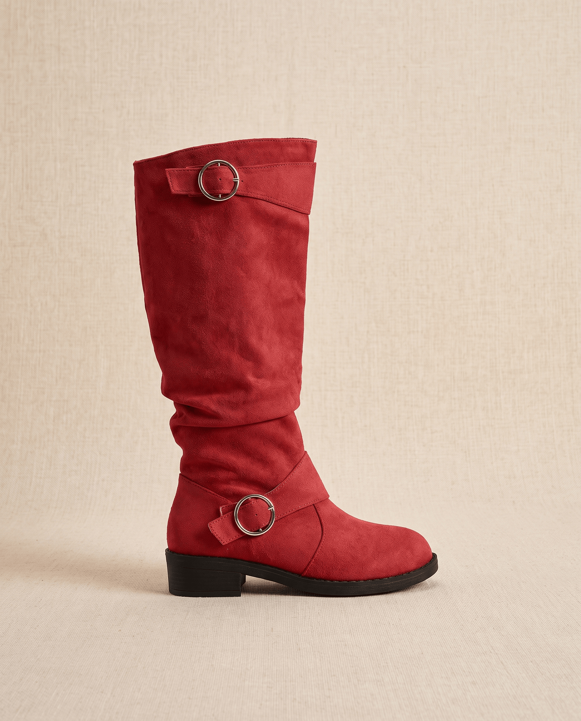 Red vegan suede knee-high boots with a slouched shaft, twin ring straps, and a low stacked heel on a neutral background.