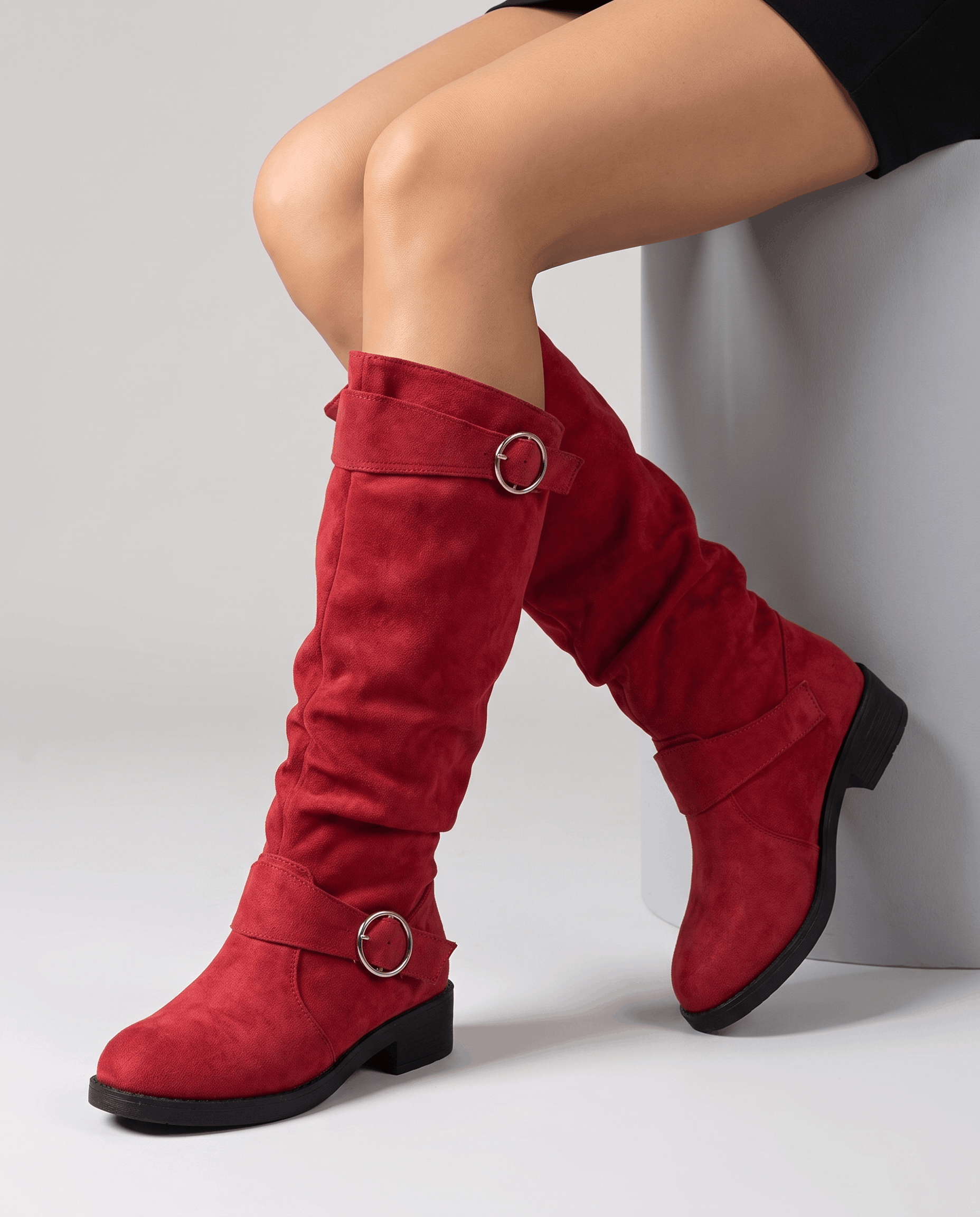 Red vegan suede knee-high boots with a slouched shaft, twin ring straps, and a low stacked heel on a round toe.