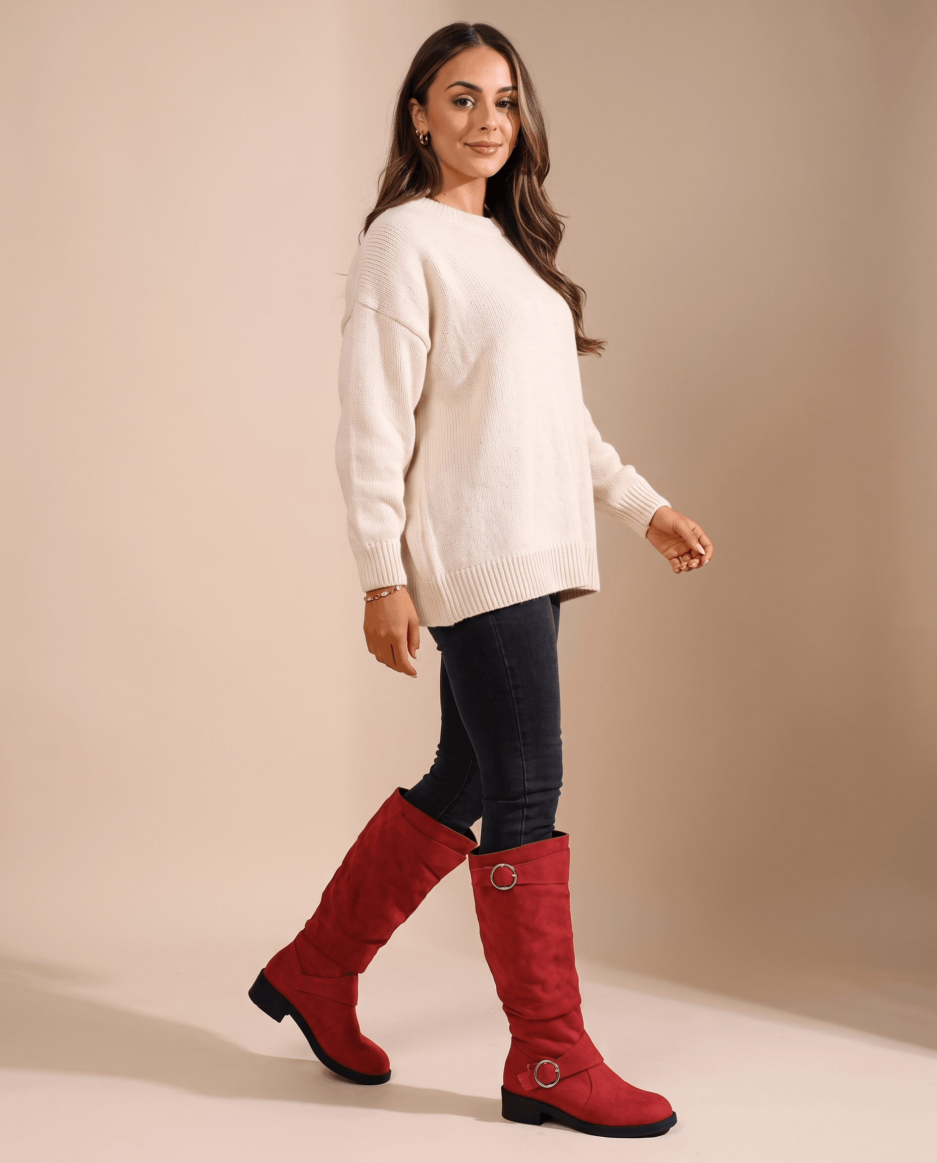 Red vegan suede knee-high boots with a slouched shaft, twin ring straps, and a low stacked heel worn with dark jeans.