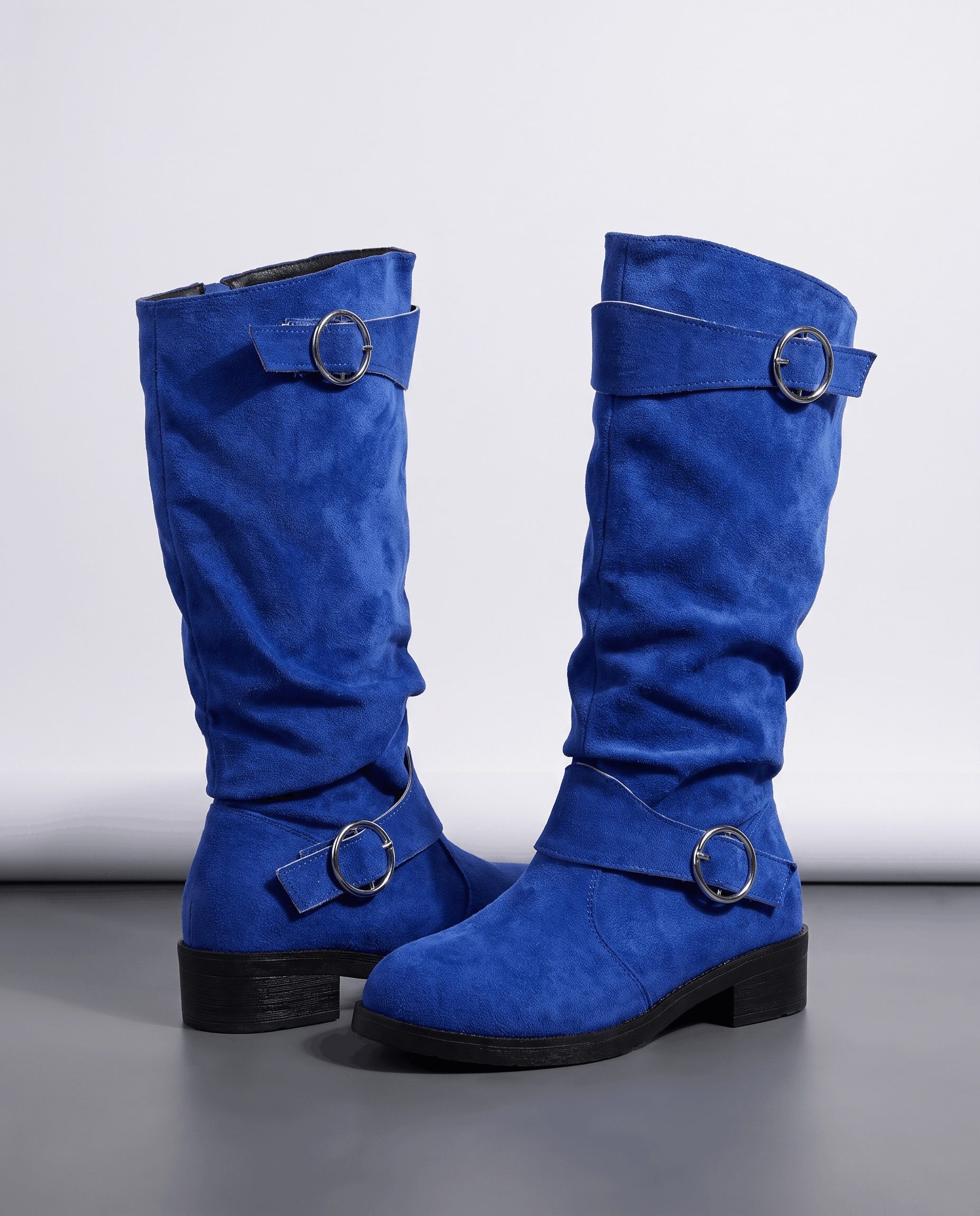 Blue vegan suede knee-high boots with a slouched shaft, twin ring straps, and a low stacked heel on a round toe.