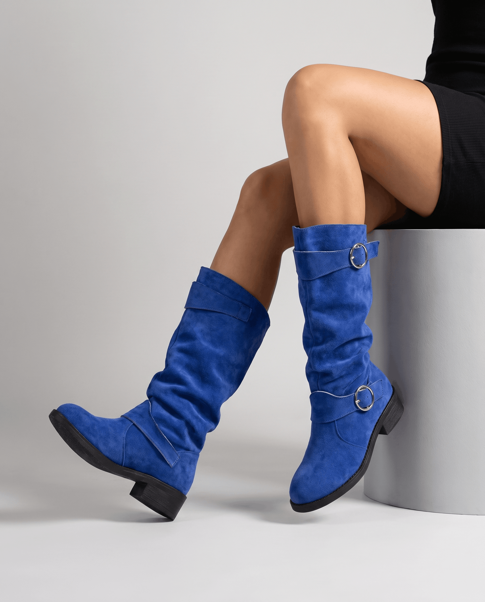 Blue vegan suede knee-high boots with a slouched shaft, twin ring straps, a round toe, and a low stacked heel.