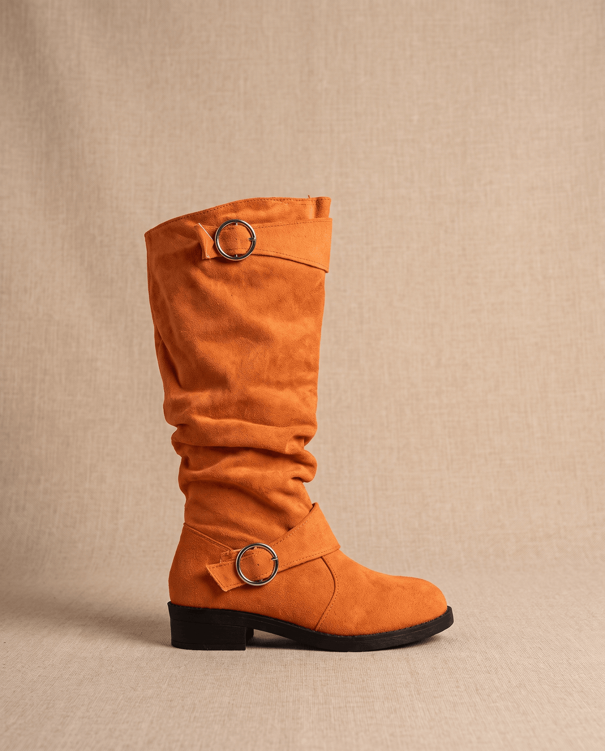 Orange vegan suede knee-high boots with a slouched shaft, twin ring straps, and a low stacked heel.
