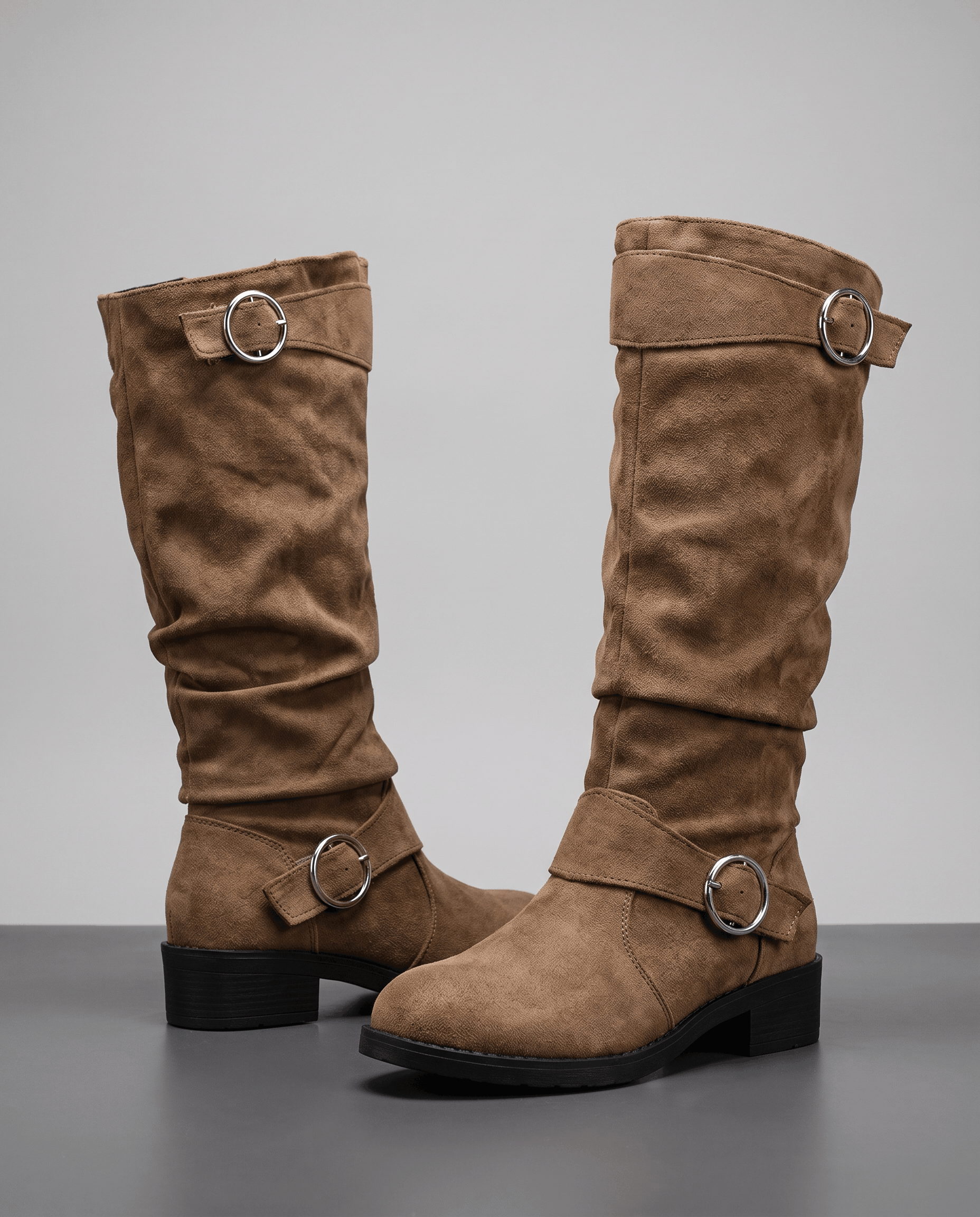 Brown vegan suede knee-high boots with a slouched shaft, round toe, low stacked heel, and silver ring strap accents.
