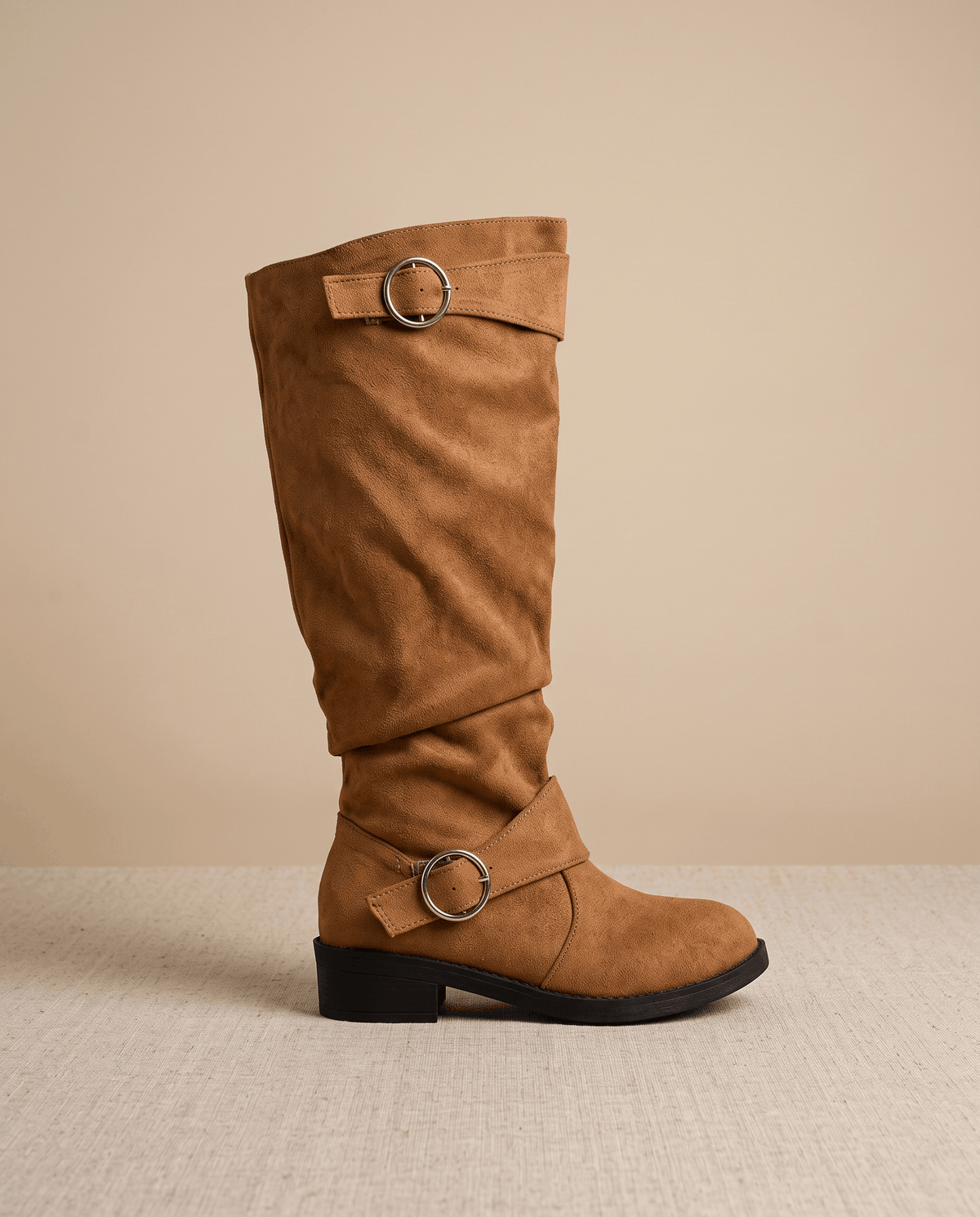 Dark brown vegan suede knee-high boots with a slouched shaft, round toe, low stacked heel, and twin ring strap accents.