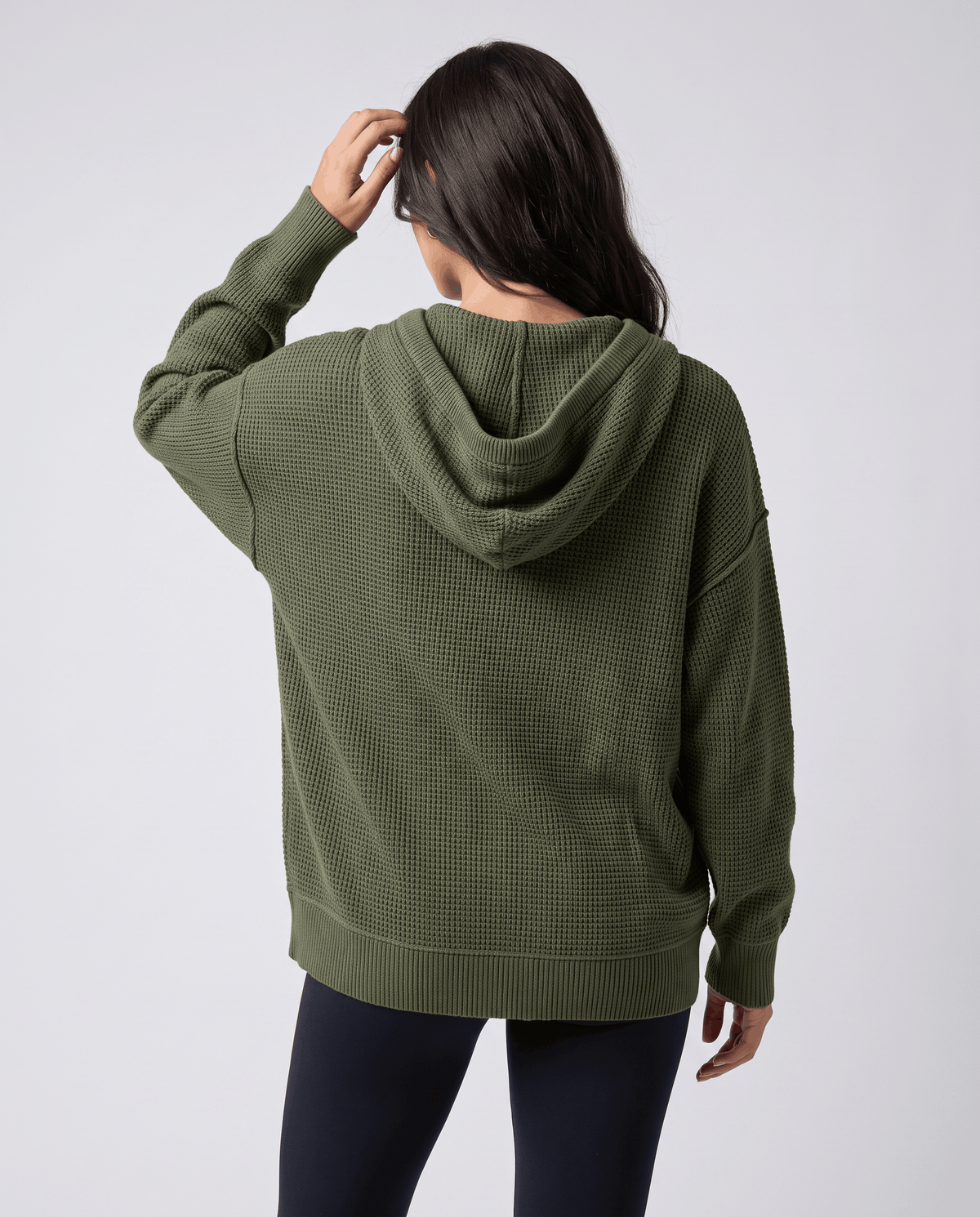 Back view of the army green knit hoodie with hood down and a hand at the head