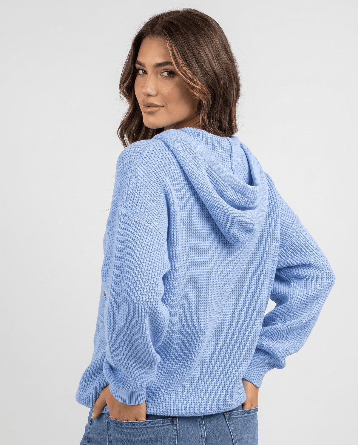 Back view of the light blue waffle knit hoodie with the hood down over jeans