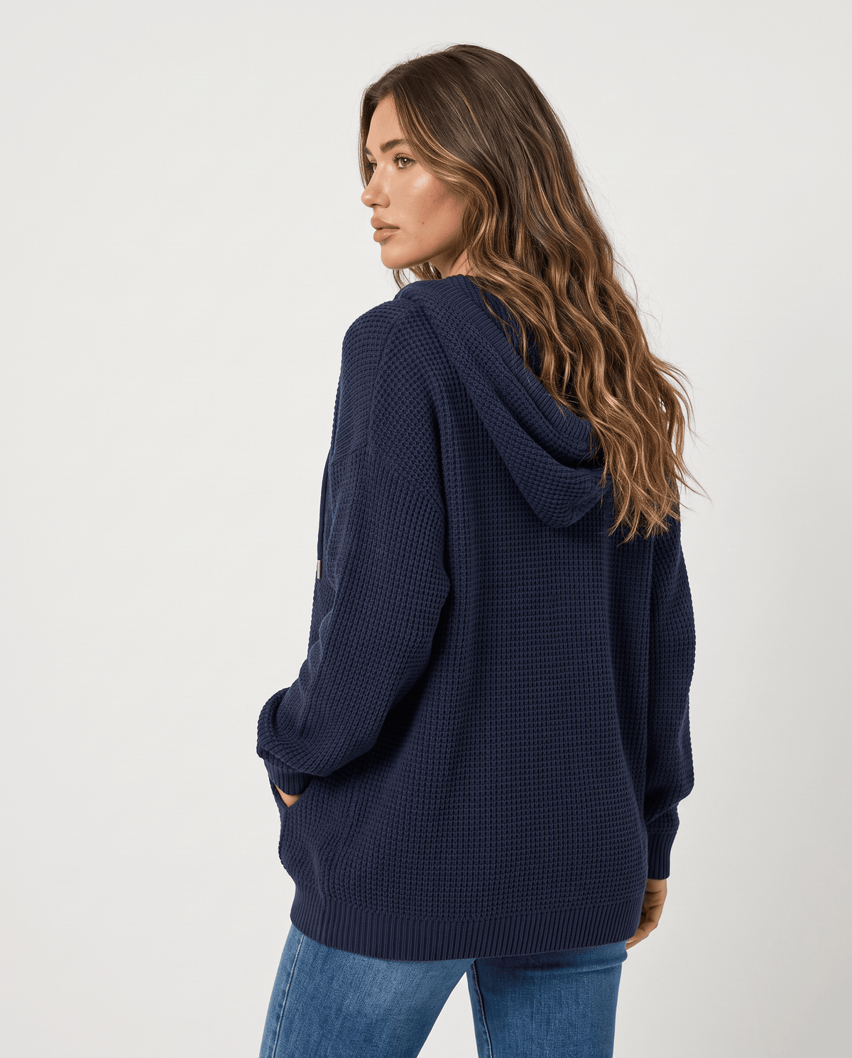 Back view of the navy waffle knit hoodie with the hood down over jeans