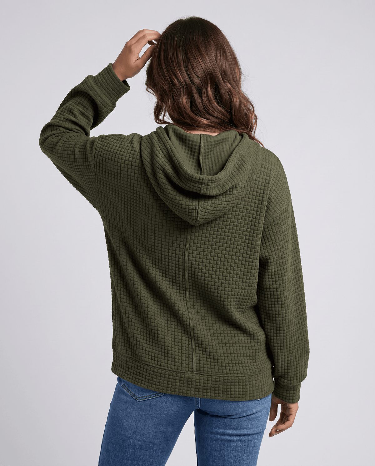 Back of dark green hoodie with a hand on the hood and ribbed cuffs
