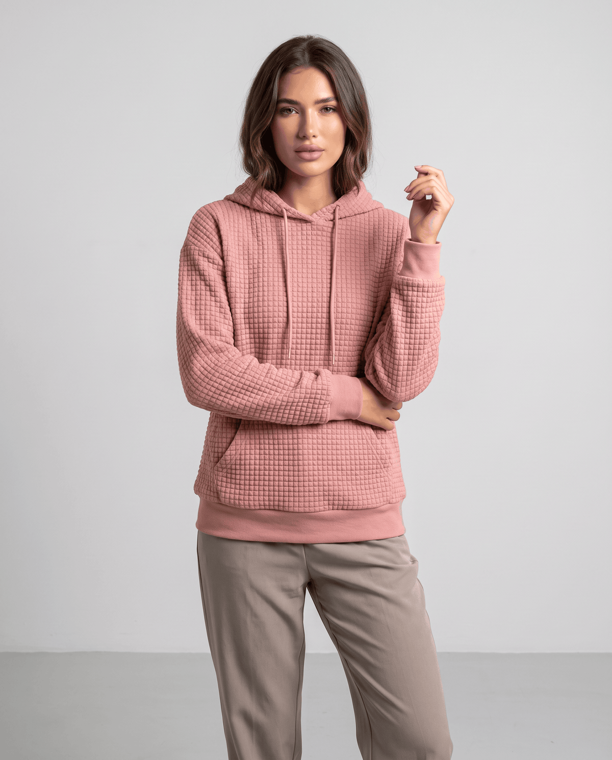 Full-length view of dusty pink hoodie styled with taupe pants and a relaxed fit